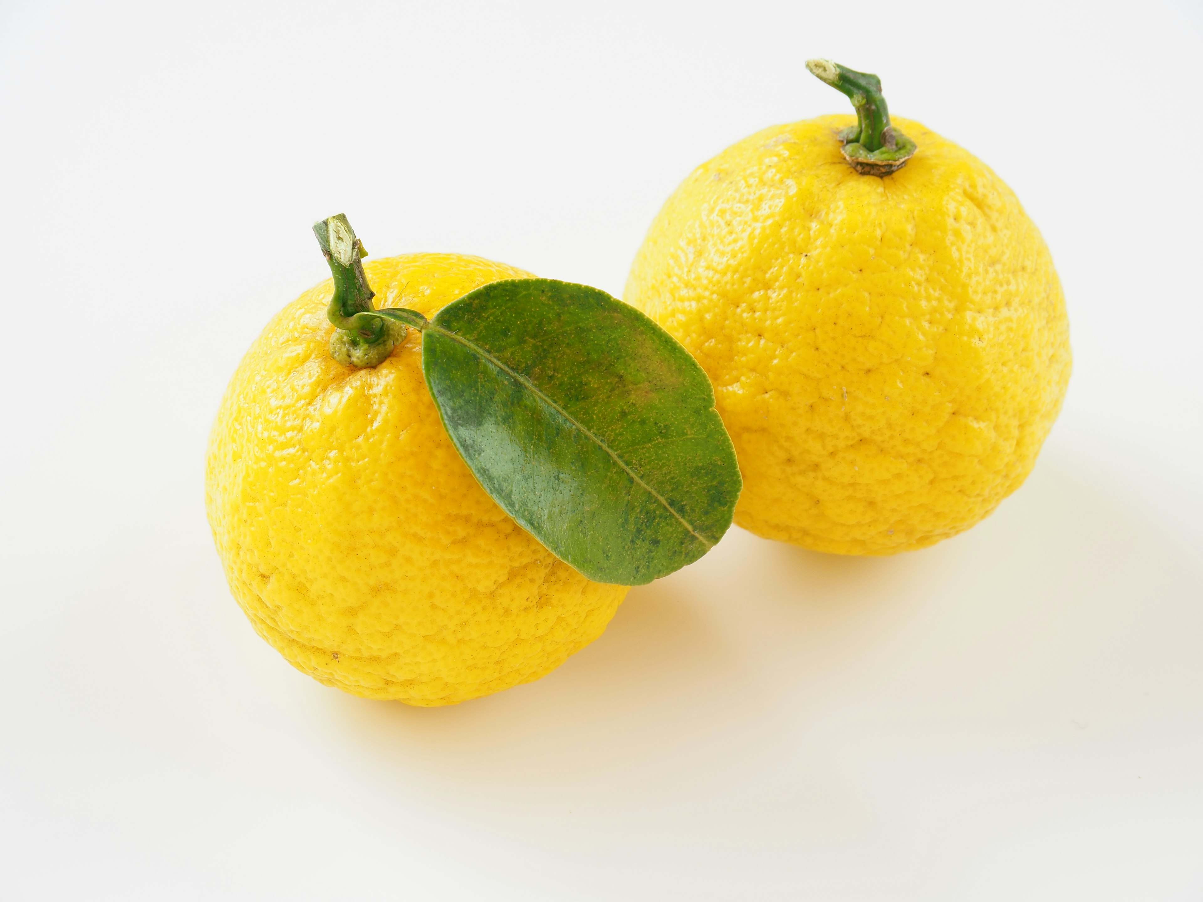 Two yellow lemons with a leaf attached