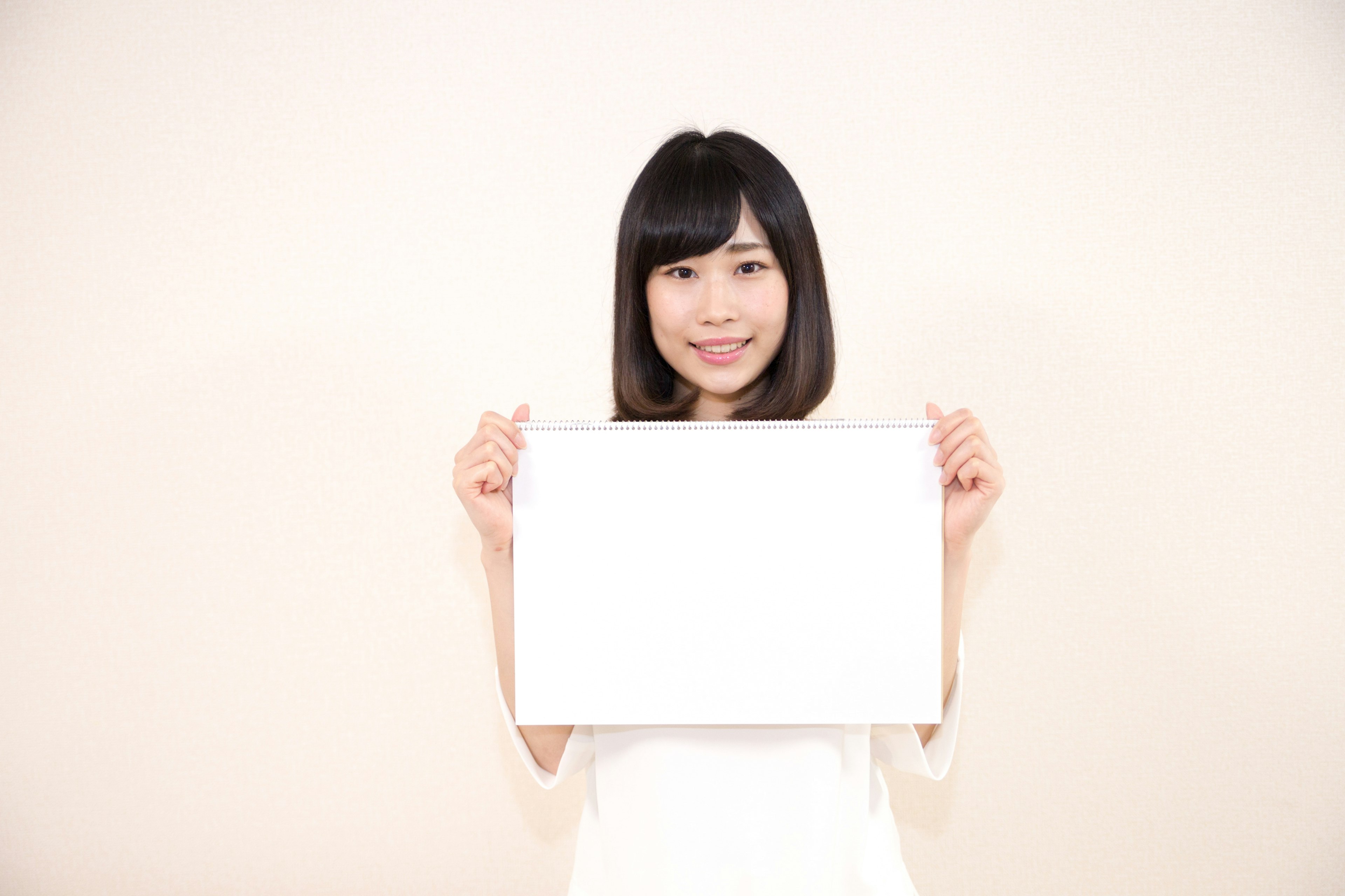 Woman holding a blank white board in front of a light background