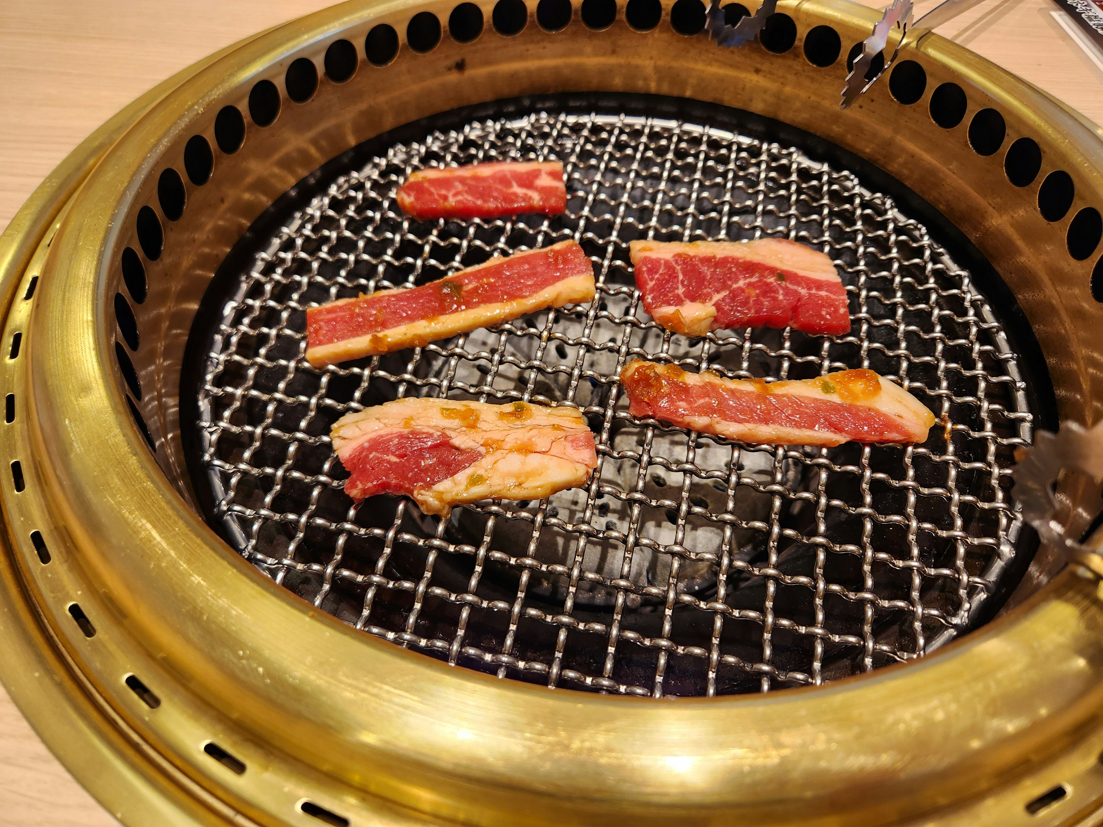 Slices of meat grilling on a Korean barbecue grill