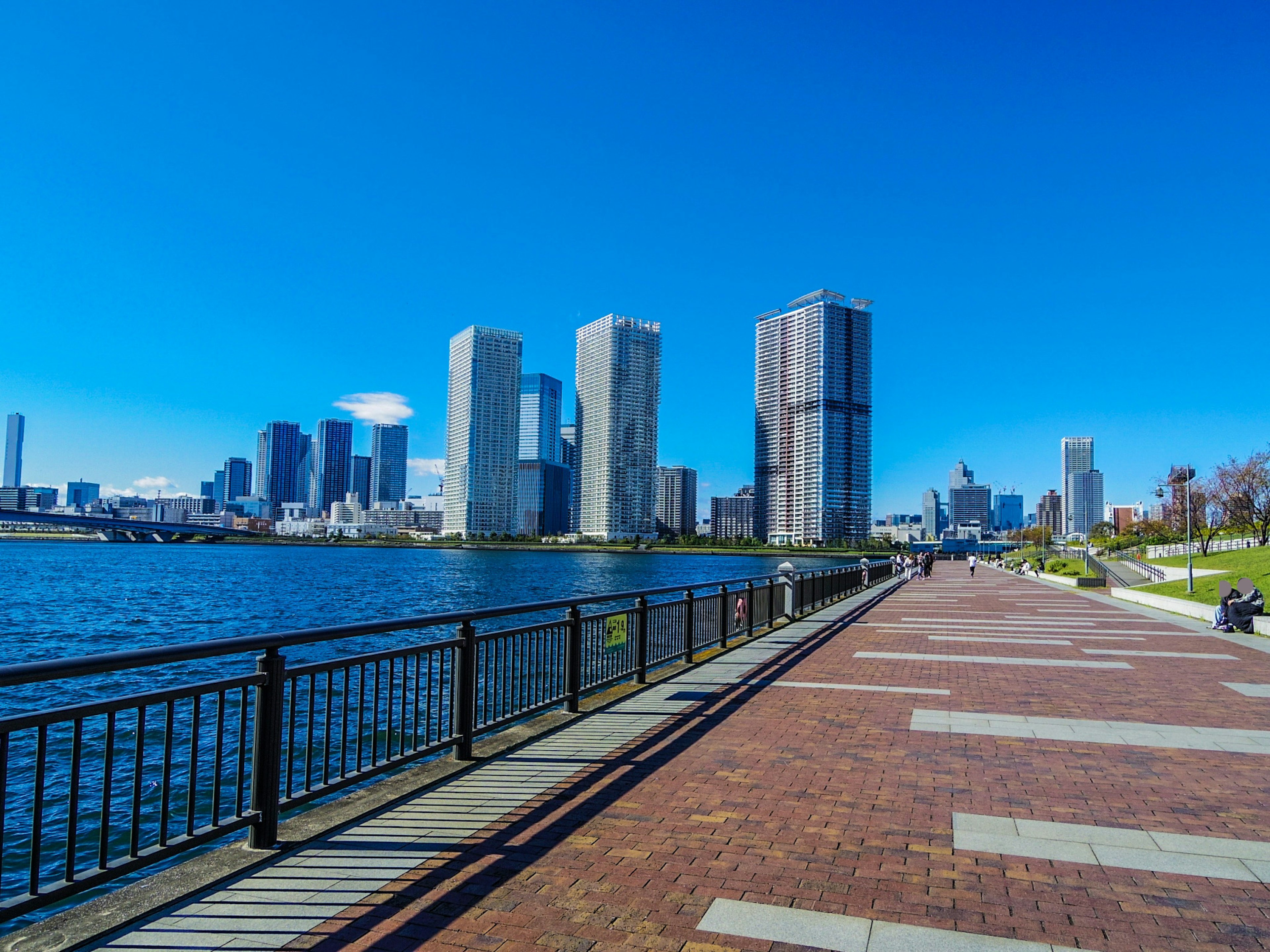 Uferpromenade mit Hochhäusern unter klarem blauen Himmel