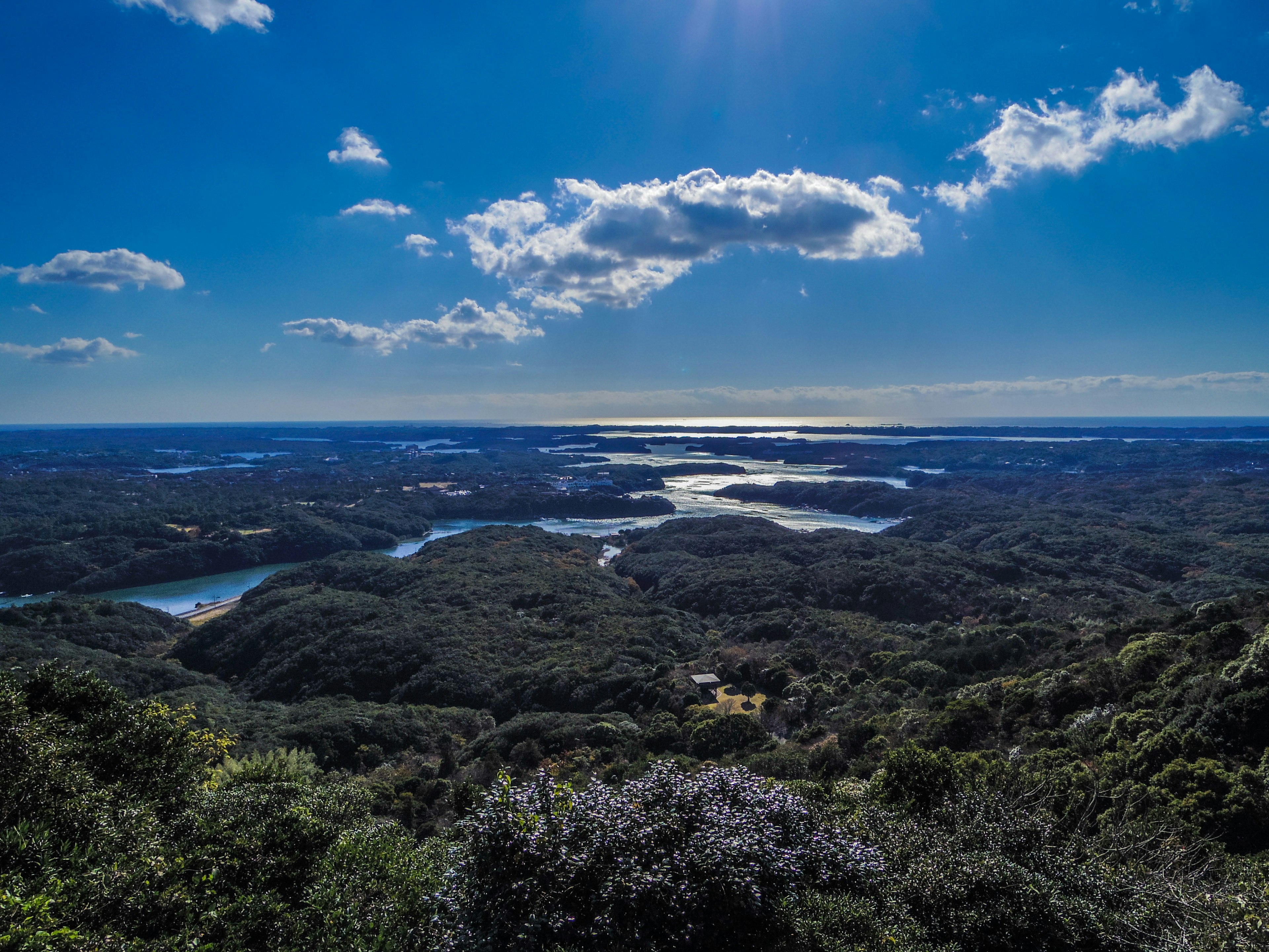 Paesaggio ampio con cielo blu e nuvole che presenta laghi e colline verdi