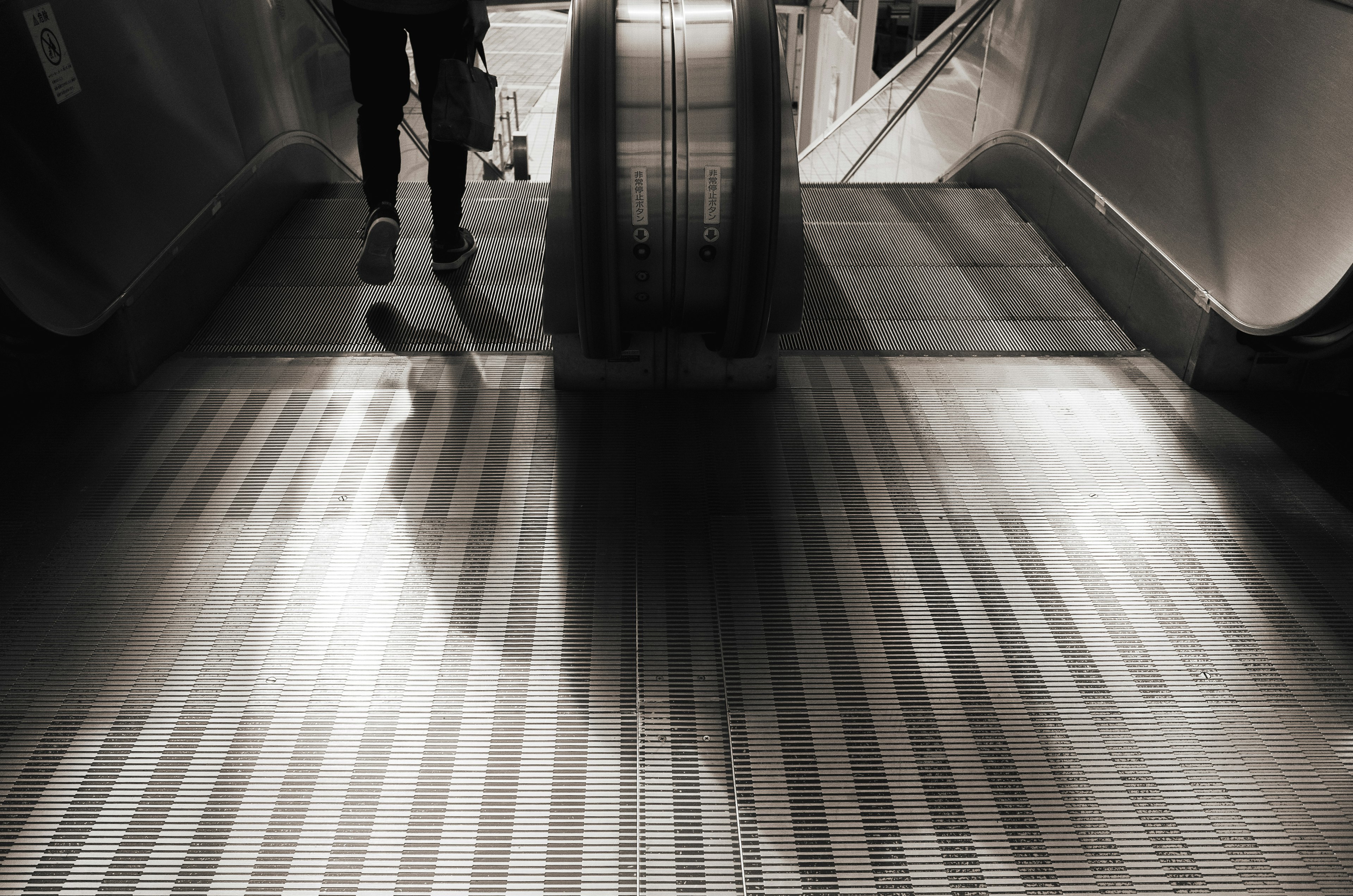 Silhouette d'une personne debout sur un escalier roulant avec un contraste de lumière et d'ombre