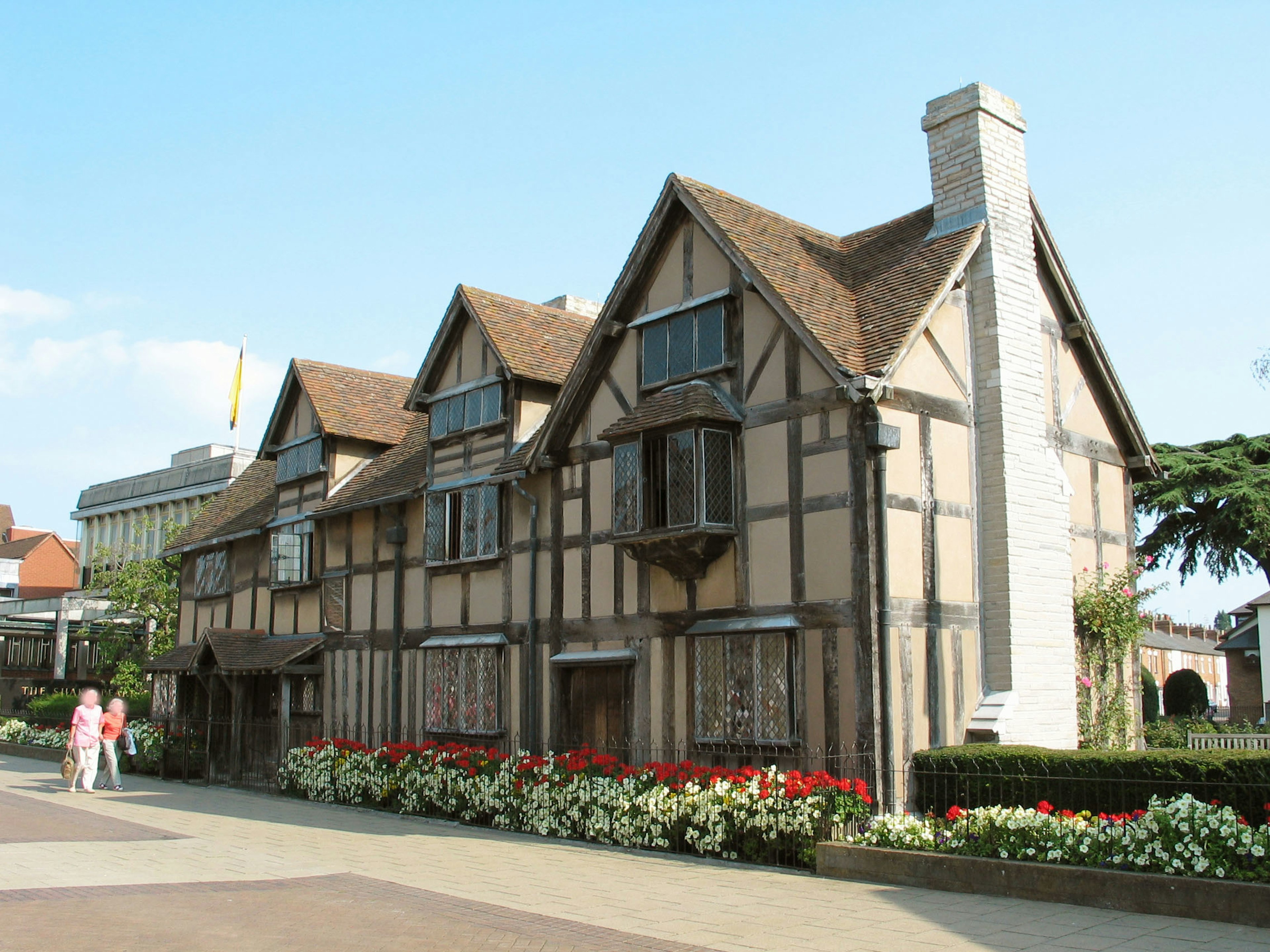 Exterior view of Shakespeare's birthplace featuring timber-framed architecture and a flower garden