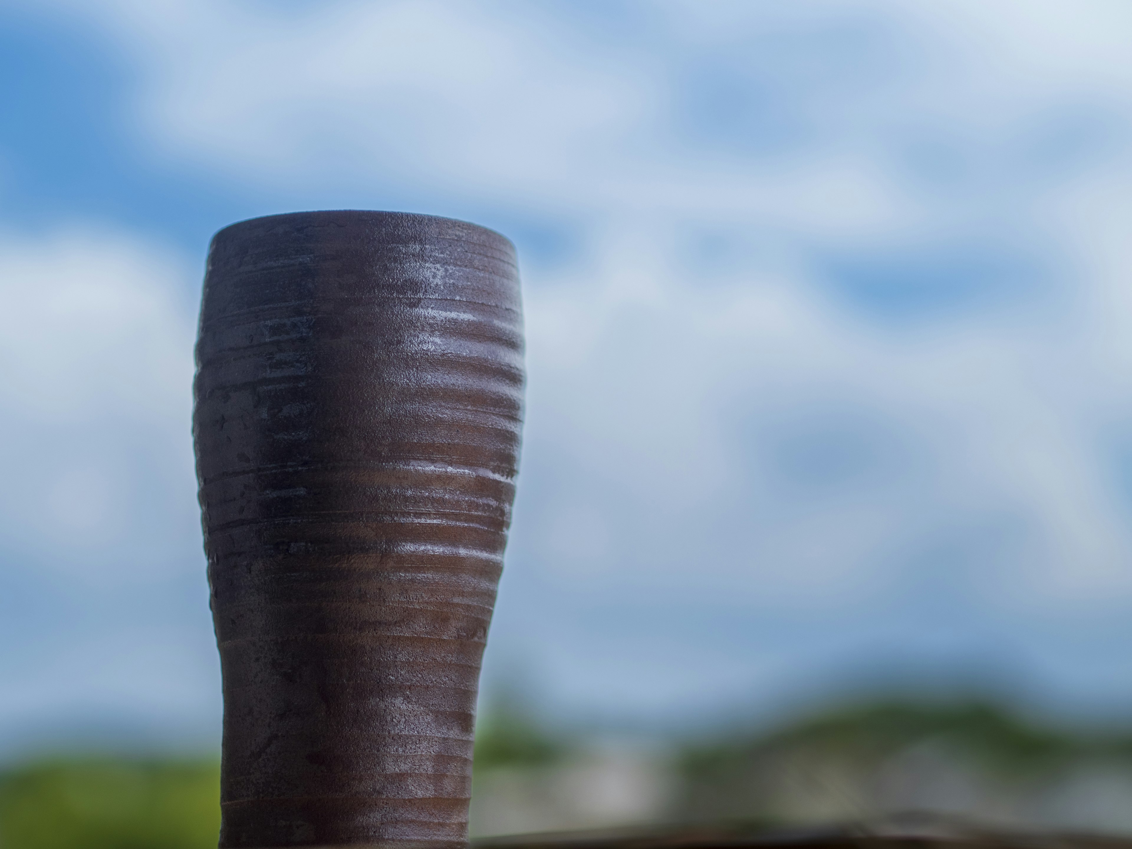 Nahaufnahme einer Holztasse vor blauem Himmel