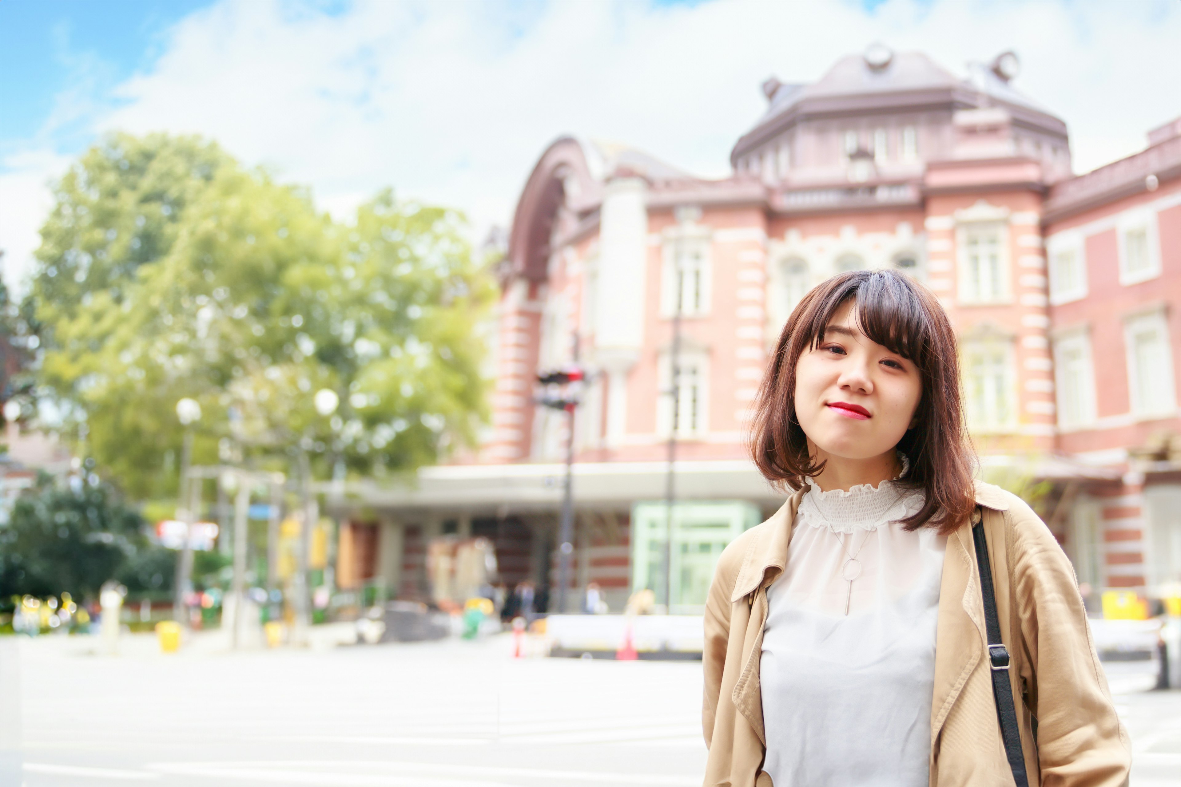 Eine Frau lächelt vor dem Bahnhof Tokio