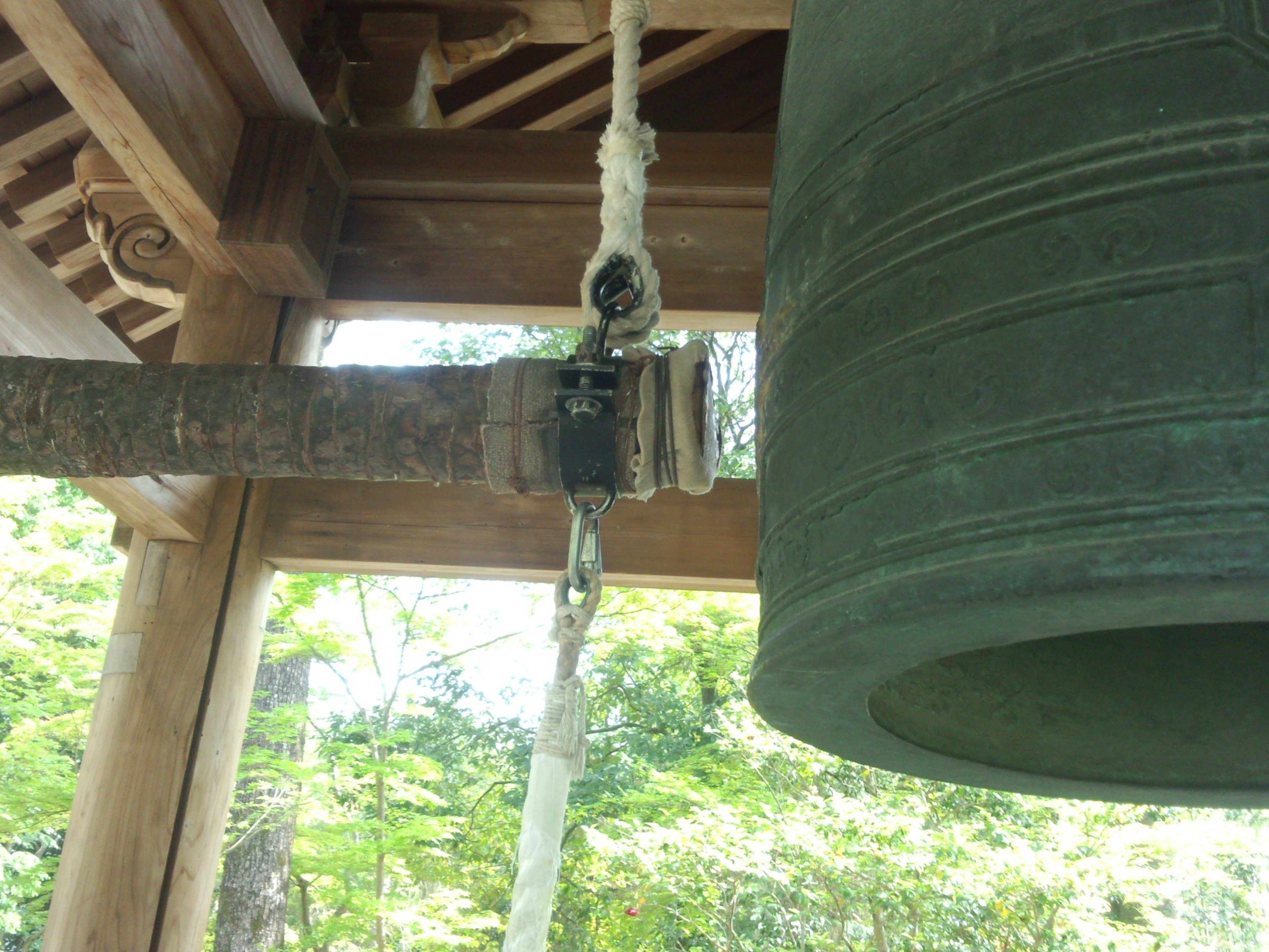 Gambar close-up dari lonceng yang tergantung dari penyangga kayu