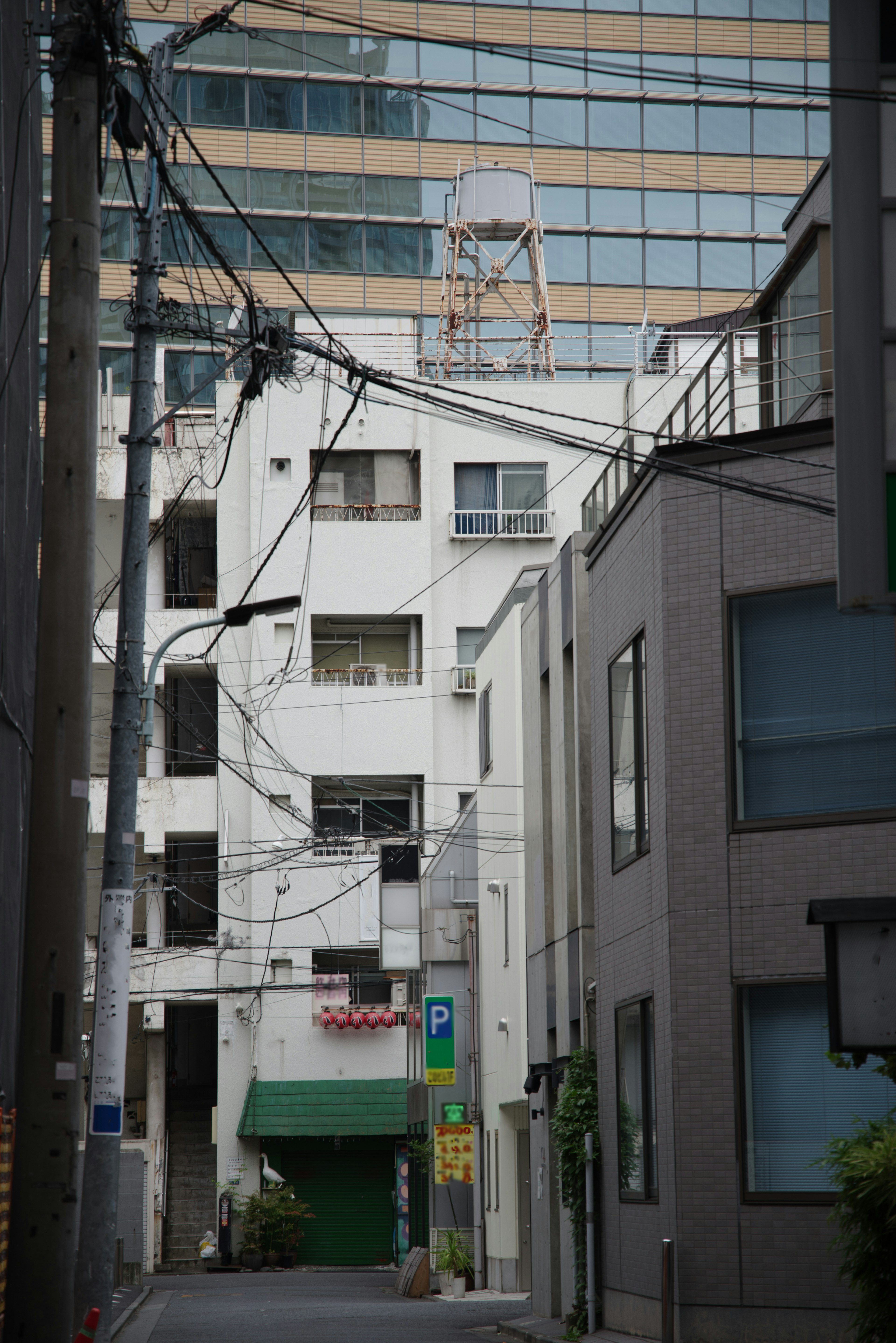 狭い路地に囲まれた白い建物とガラスの高層ビルが見える