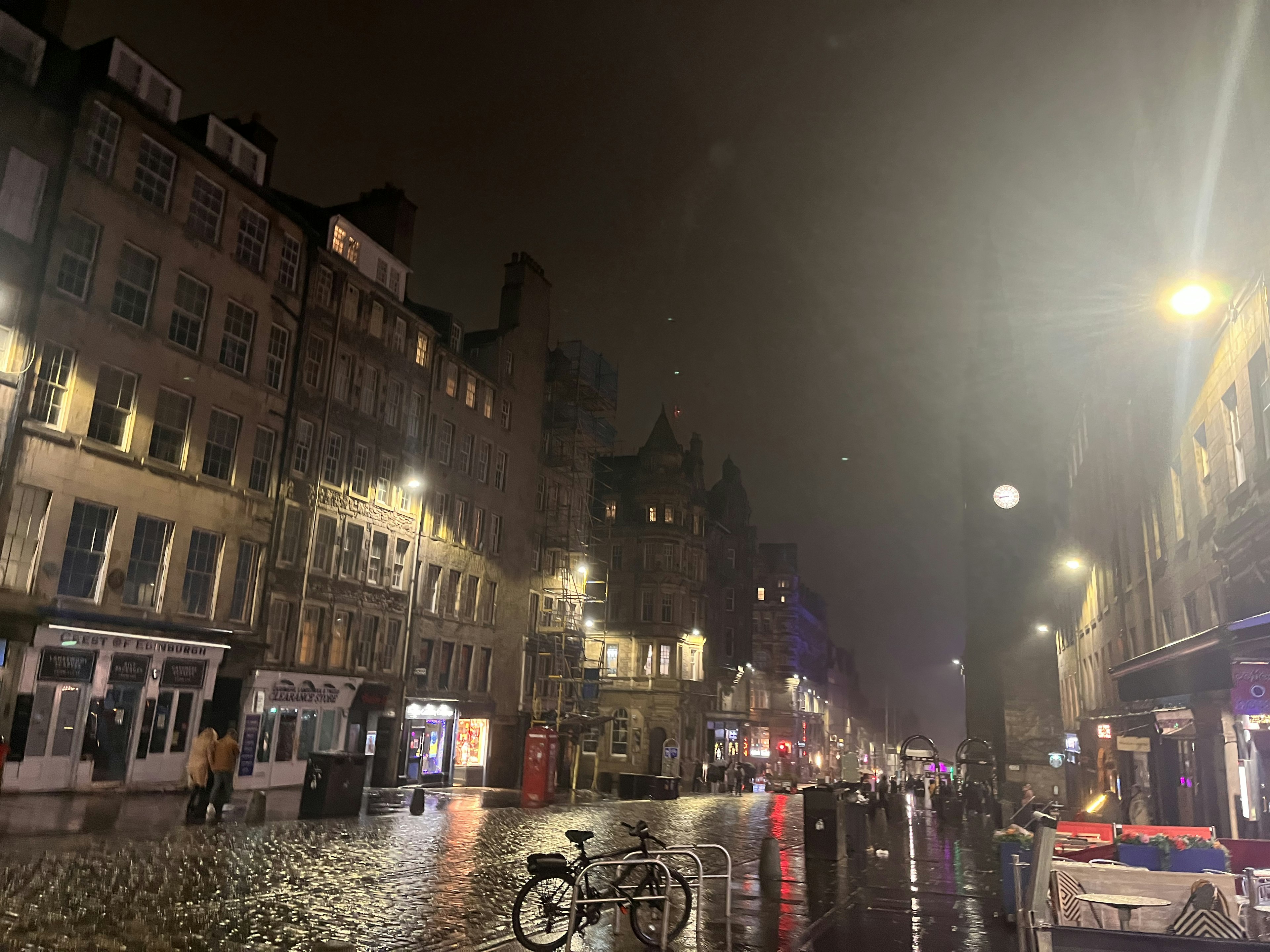 Edinburgh street at night with glowing streetlights and wet cobblestone pavement