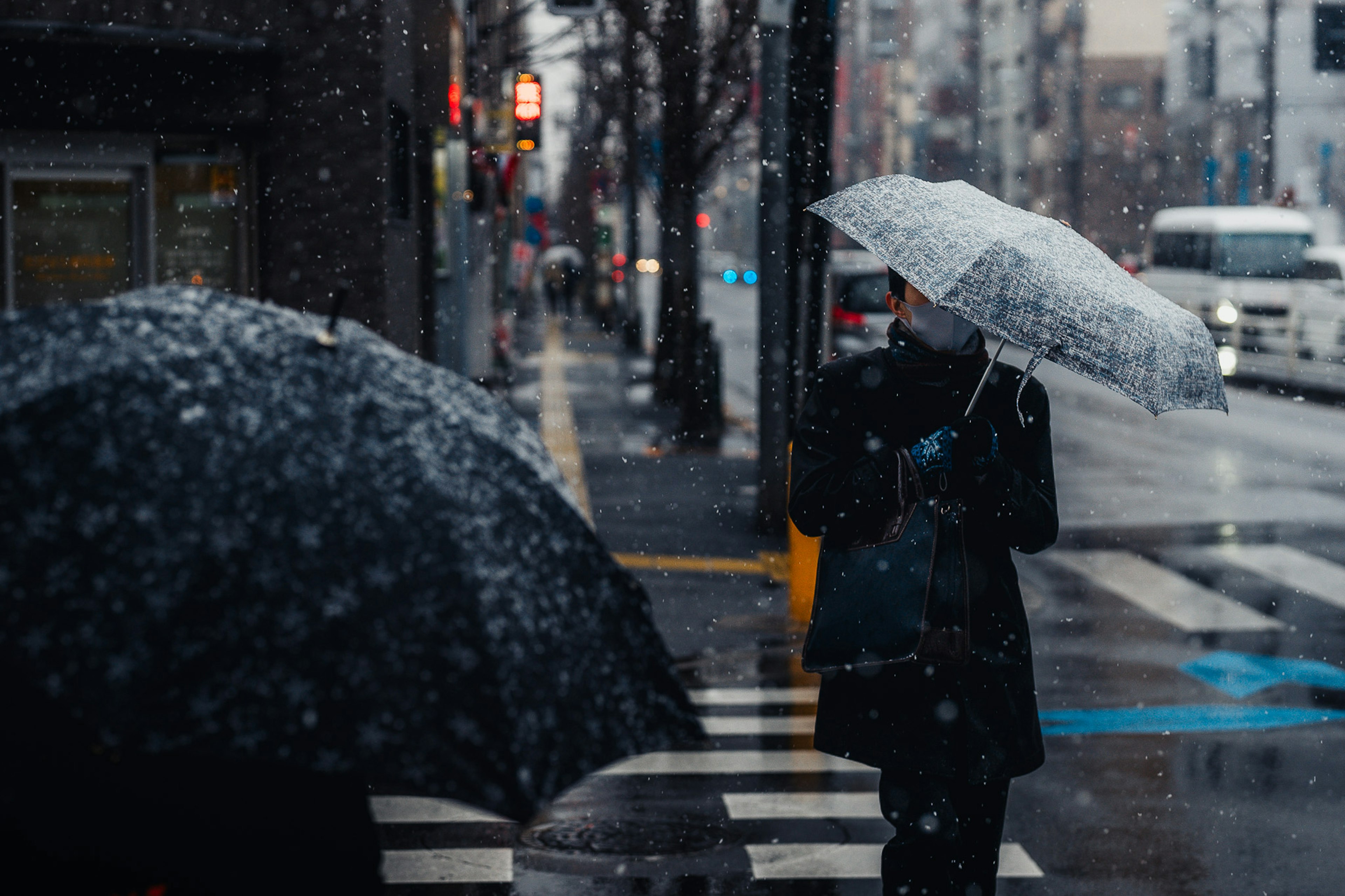 一个人拿着伞在雪中过马路