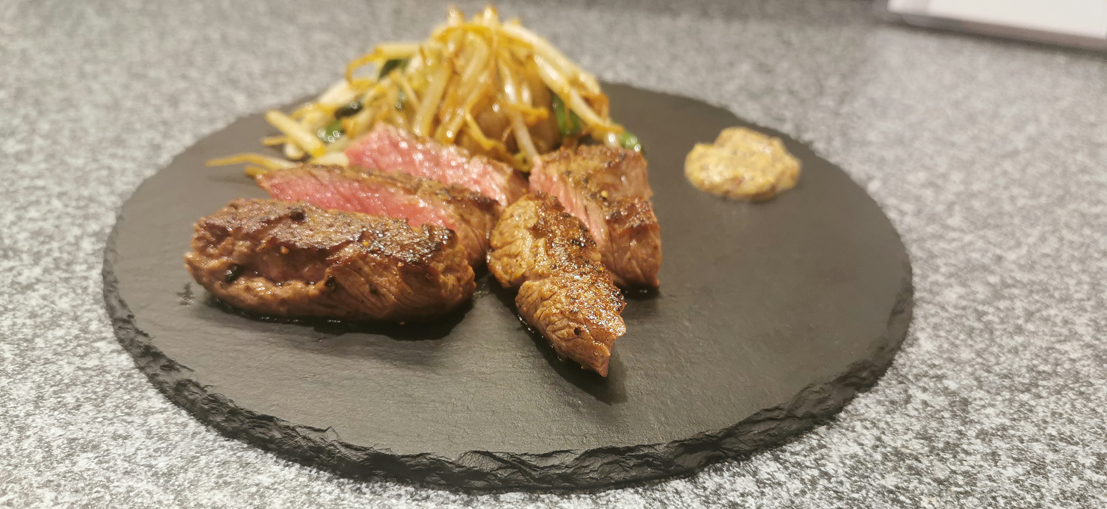 Carne asada y verduras servidas en un plato negro