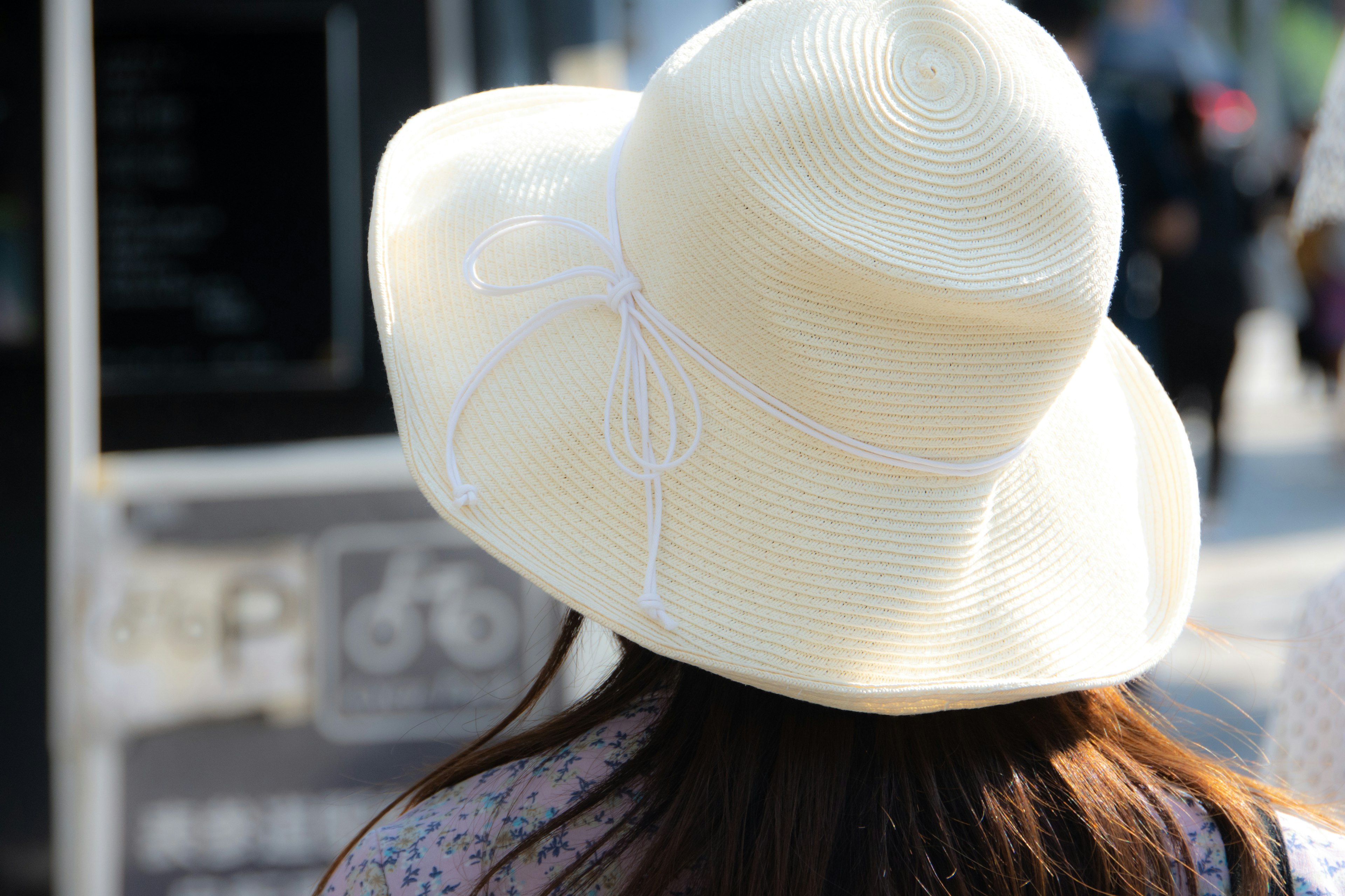 Una mujer con un gran sombrero blanco vista desde atrás