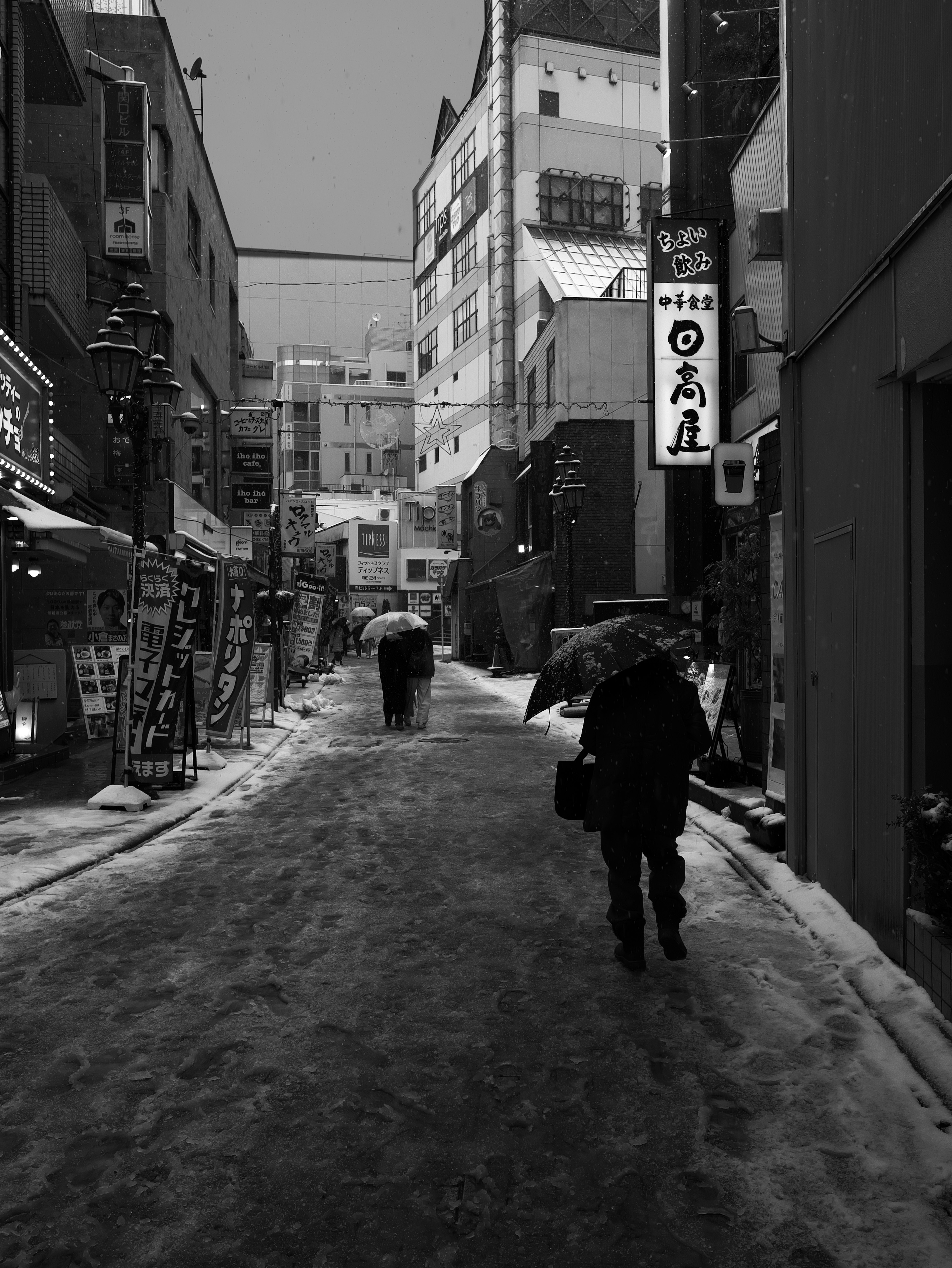 Foto in bianco e nero di una strada innevata con persone che camminano