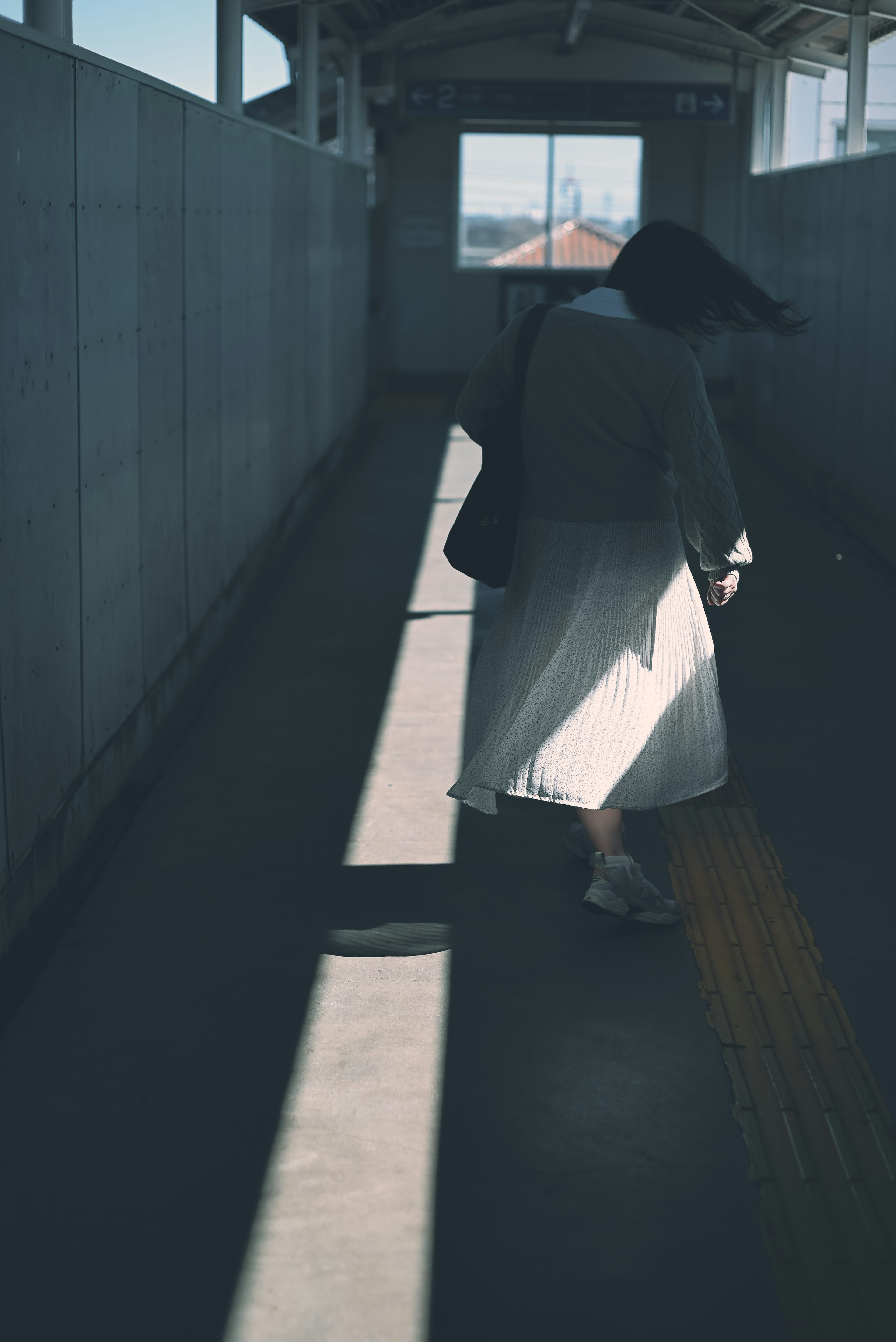 Silueta de una persona caminando por un pasillo débilmente iluminado con contraste de luz