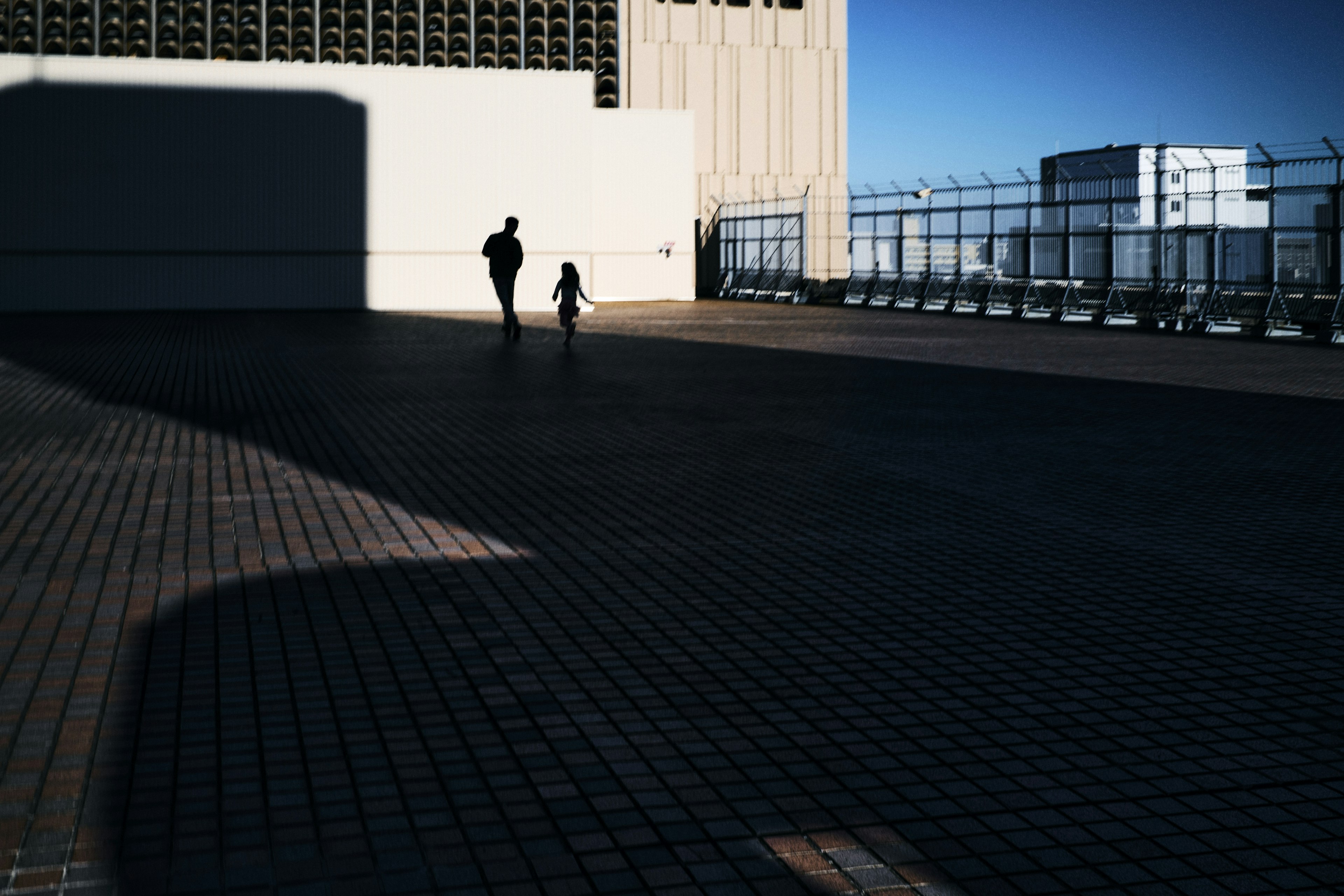 Silueta de una persona y un niño caminando en una azotea