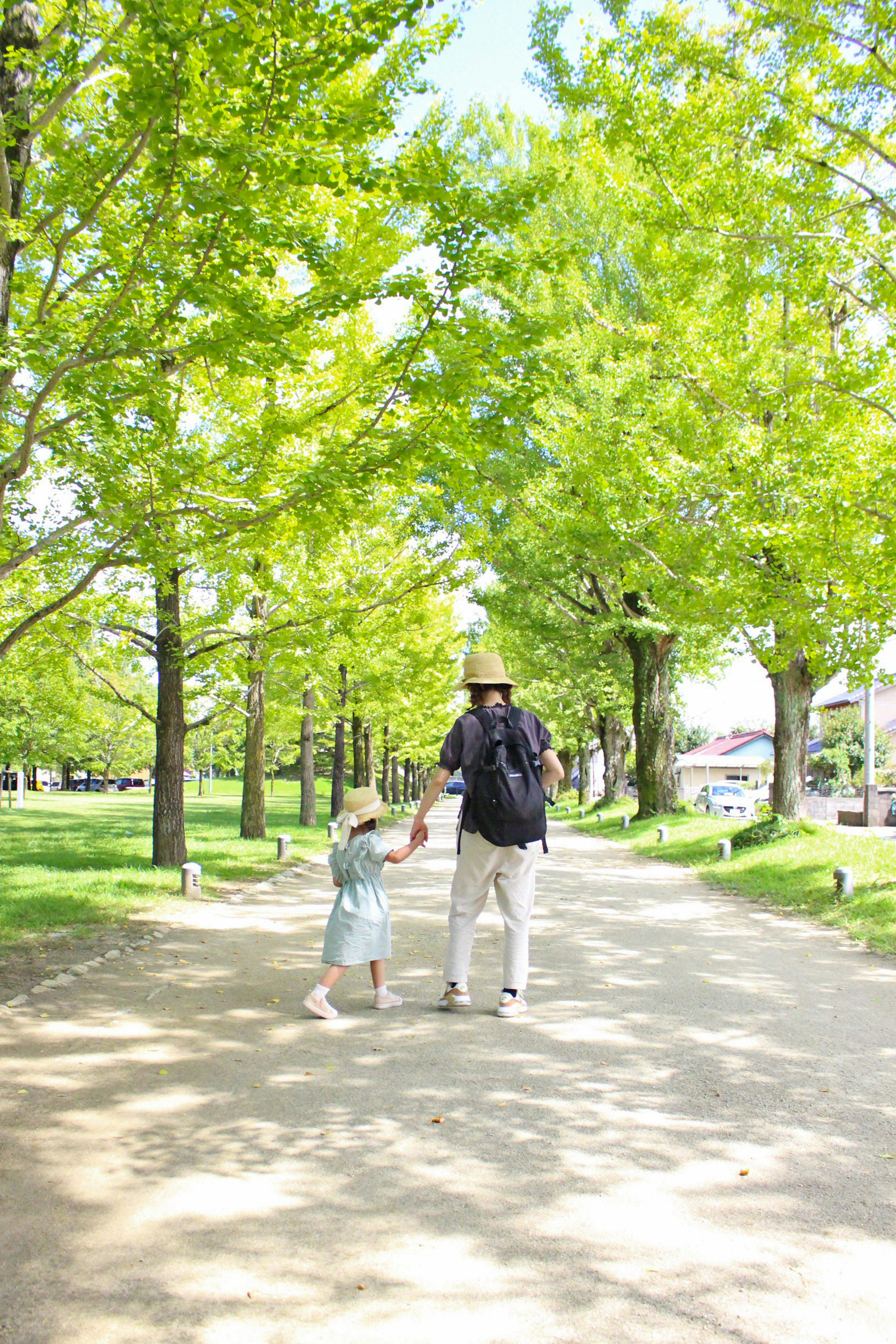 Parent et enfant se tenant par la main dans un parc entouré d'arbres verts