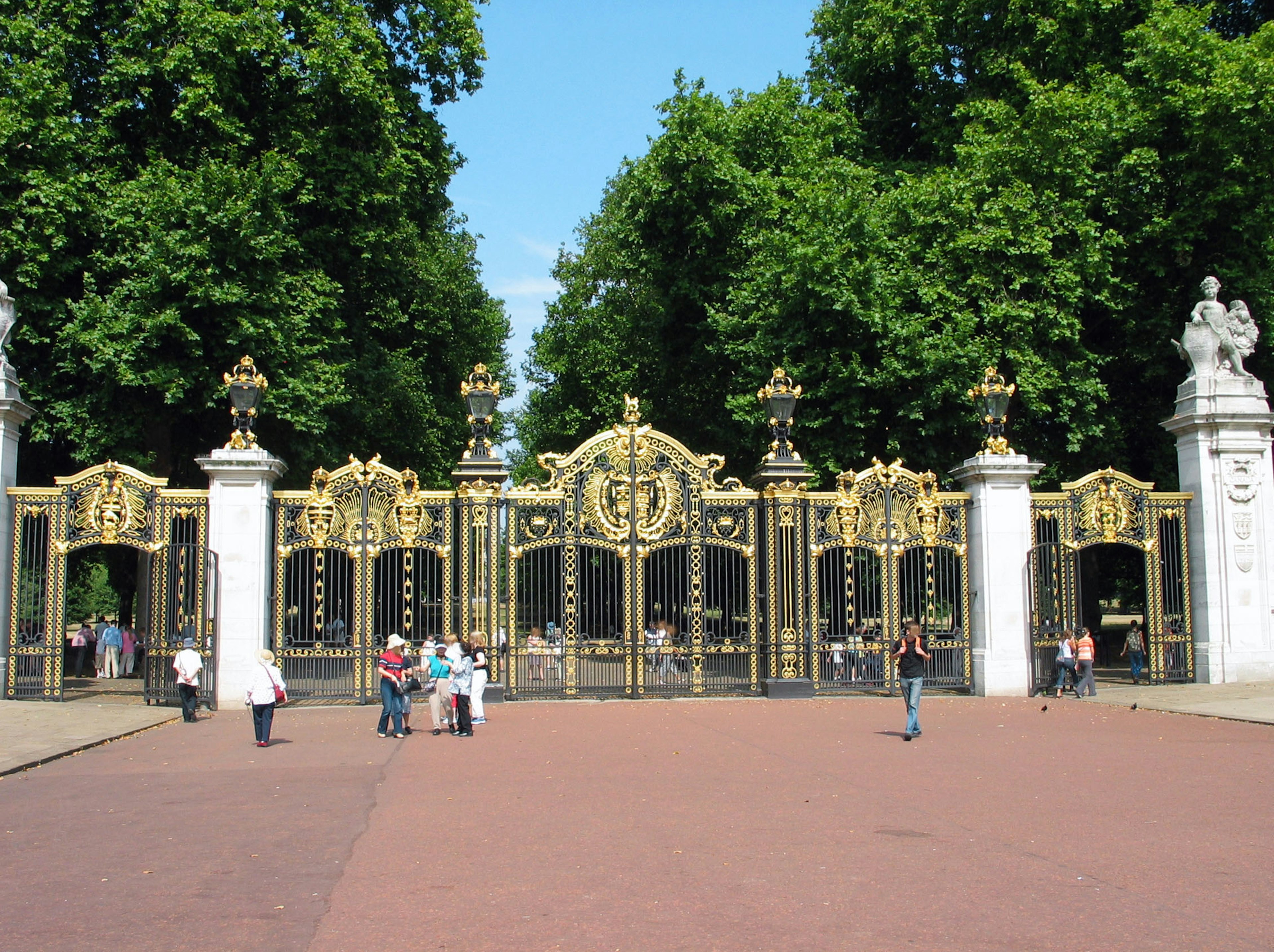 Large ornate golden gates with lush green trees in the background