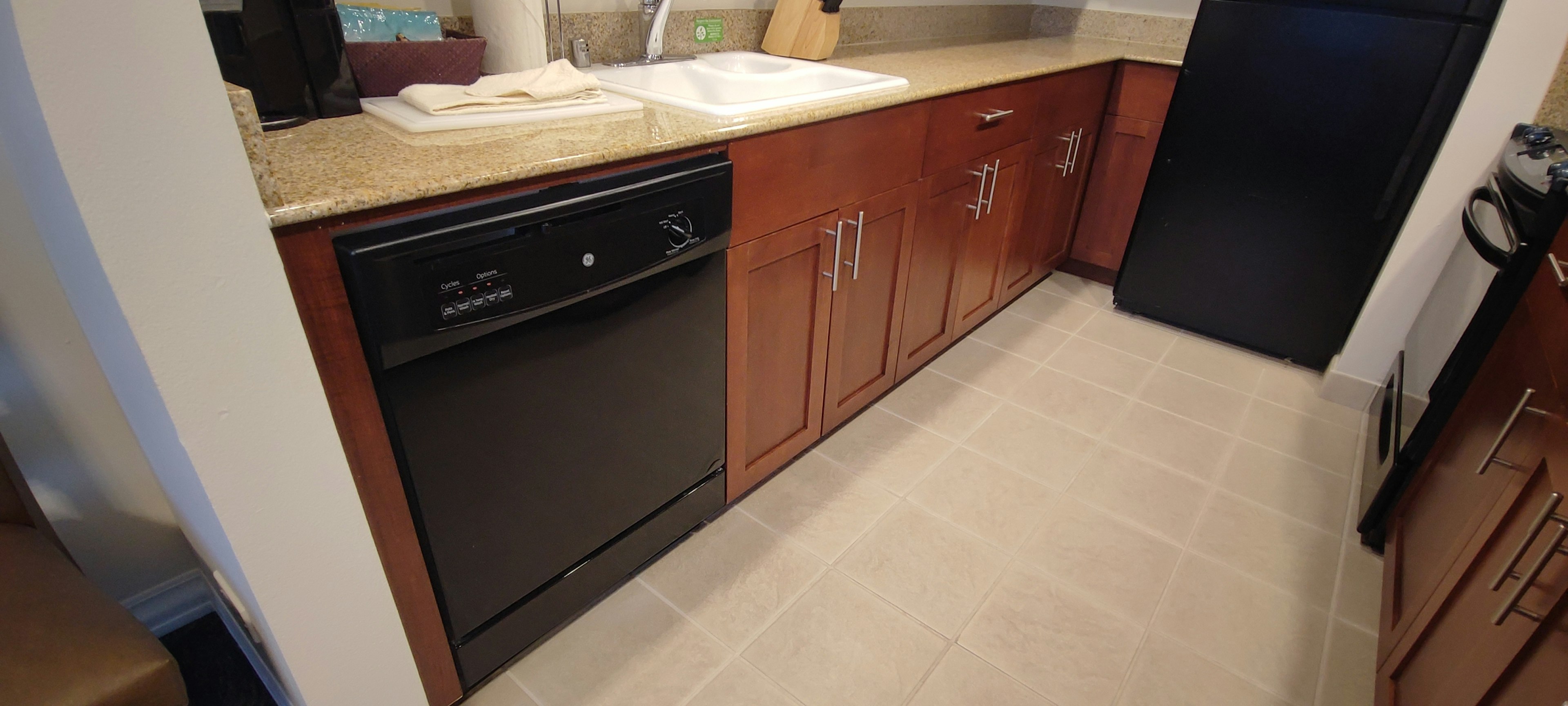 Modern kitchen featuring a dark dishwasher and wooden cabinets