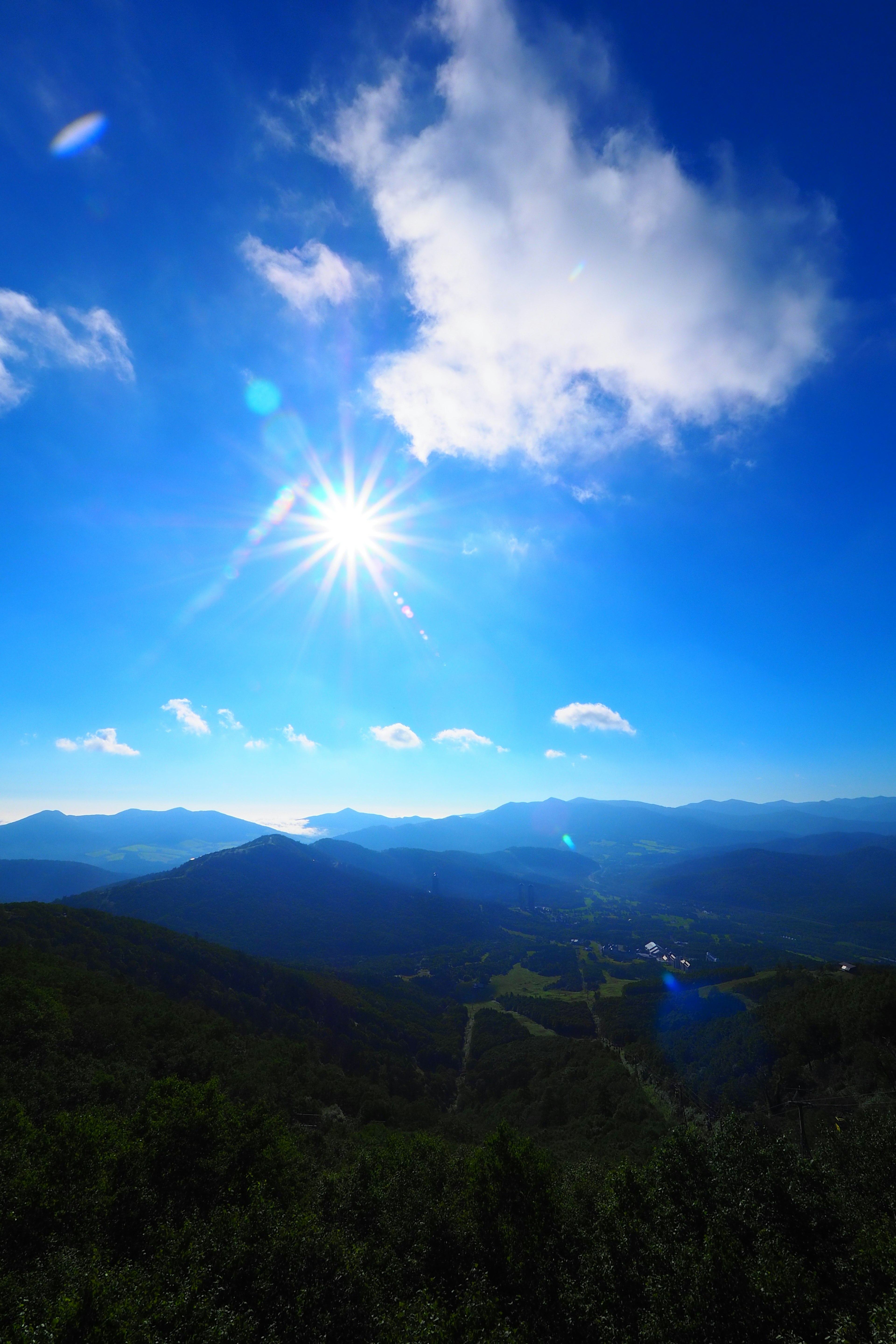 Vista panoramica delle montagne sotto un cielo blu brillante con un sole splendente