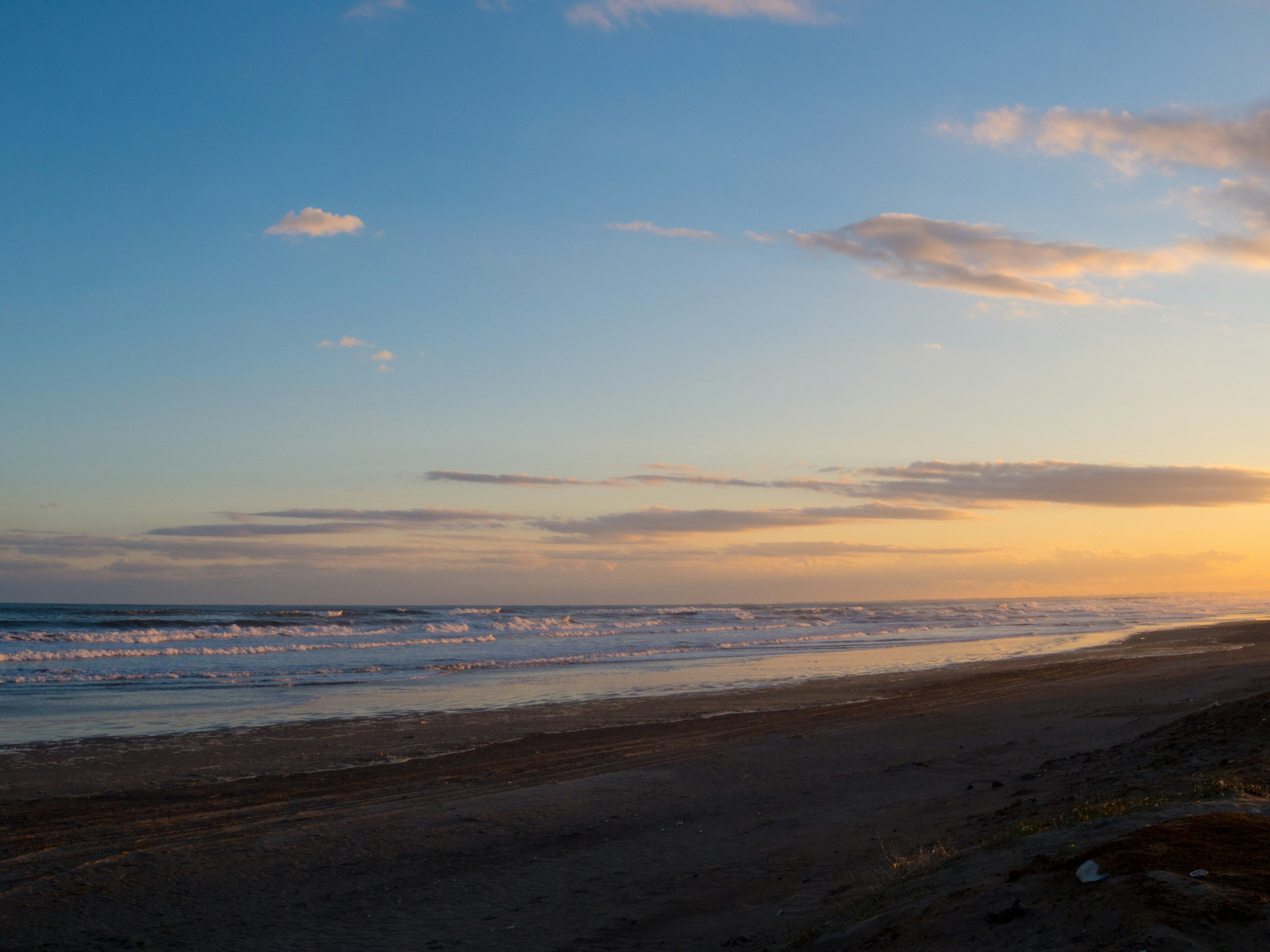 Tranquil beach scene with ocean waves and sunset sky