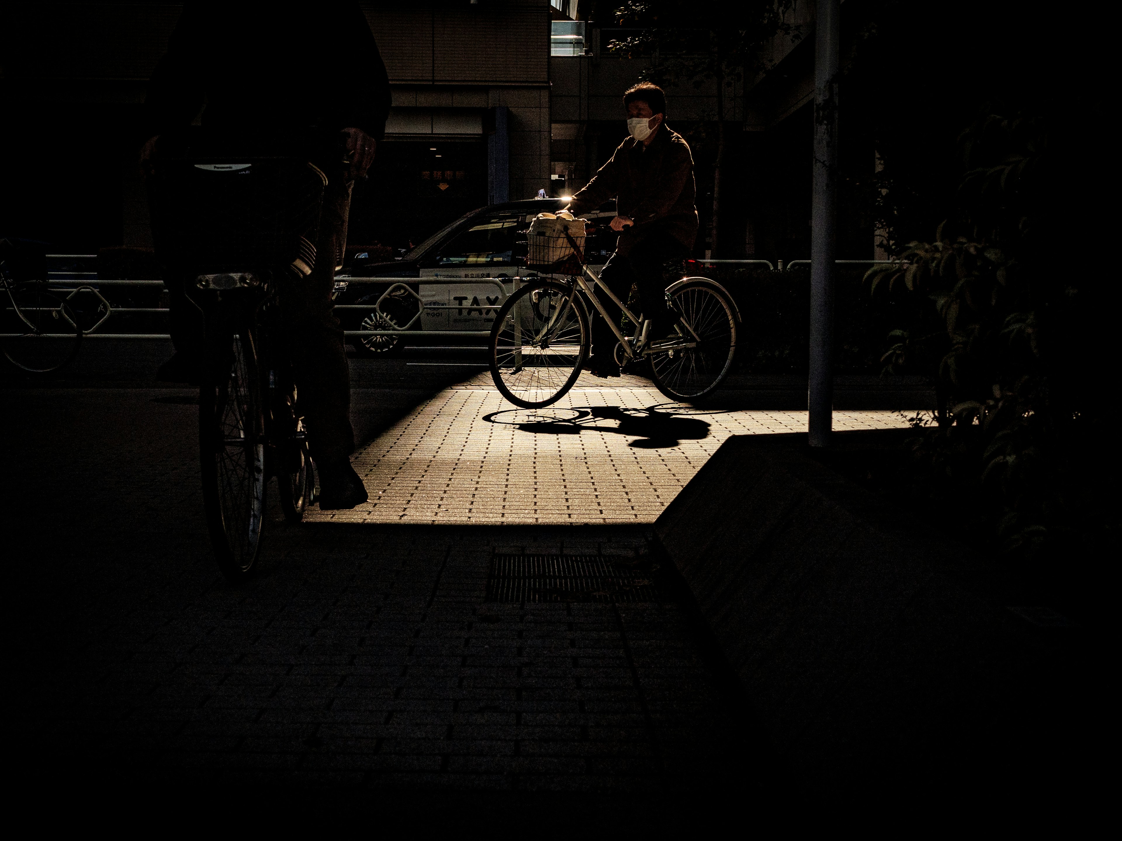 Un cycliste passant sous un spot lumineux dans un cadre urbain sombre