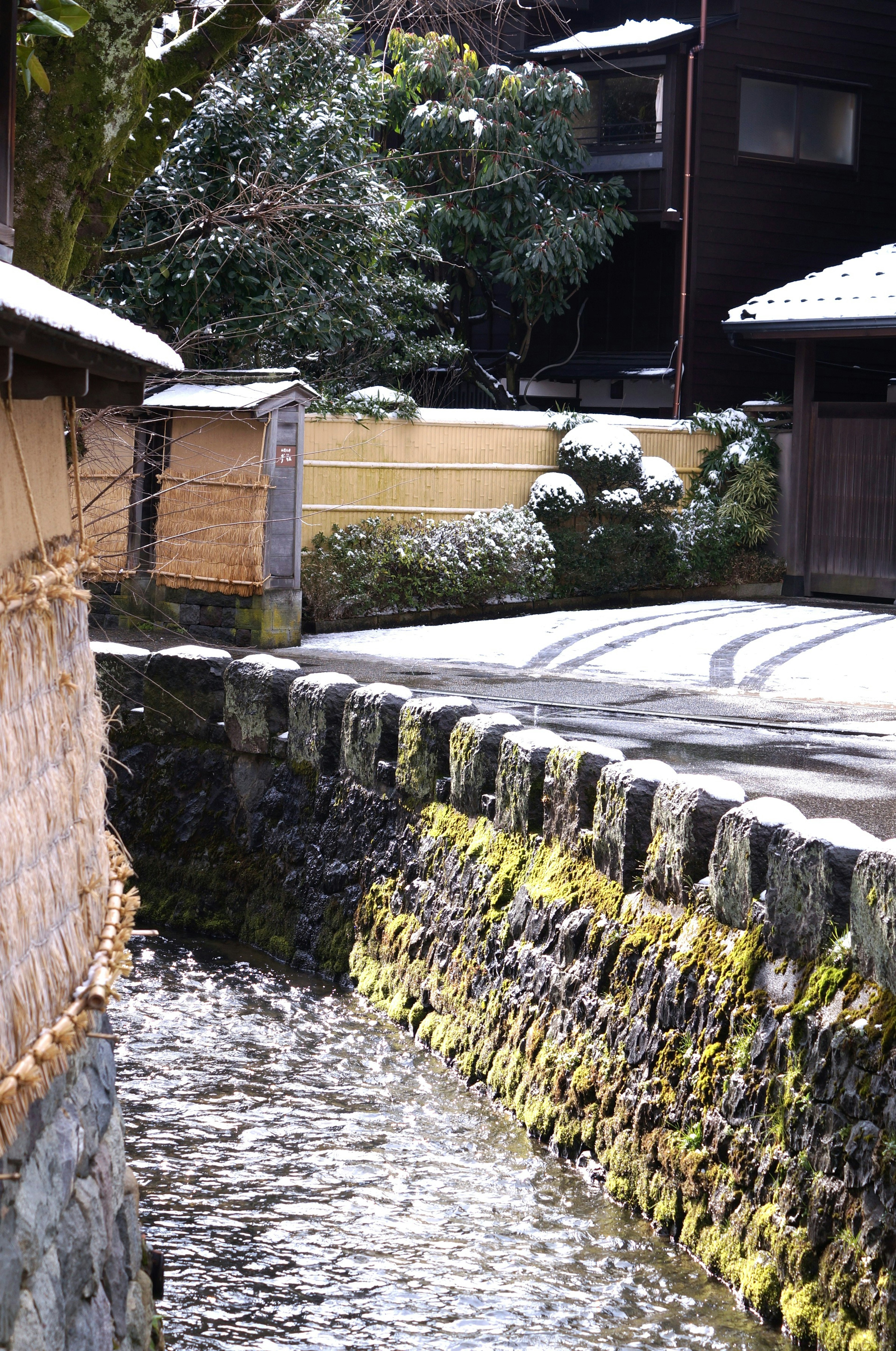 Snow-covered stone wall with a tranquil waterway