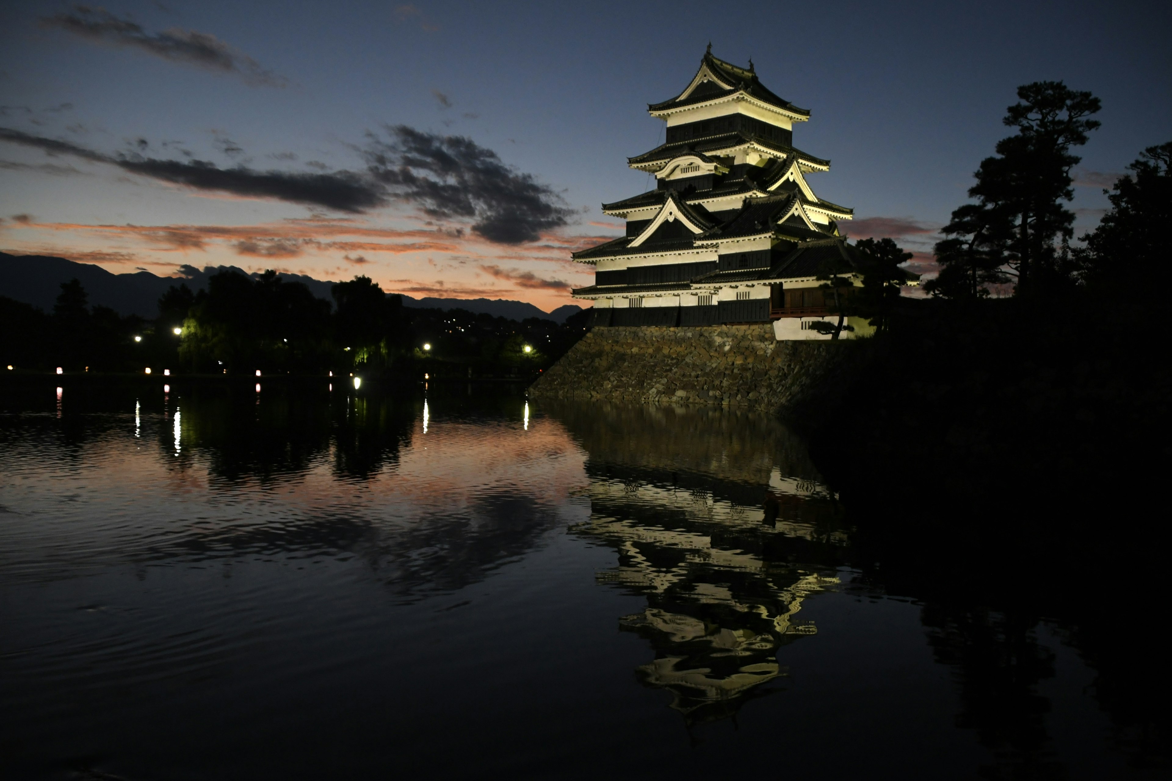 Castello di Matsumoto illuminato al crepuscolo con riflesso nell'acqua