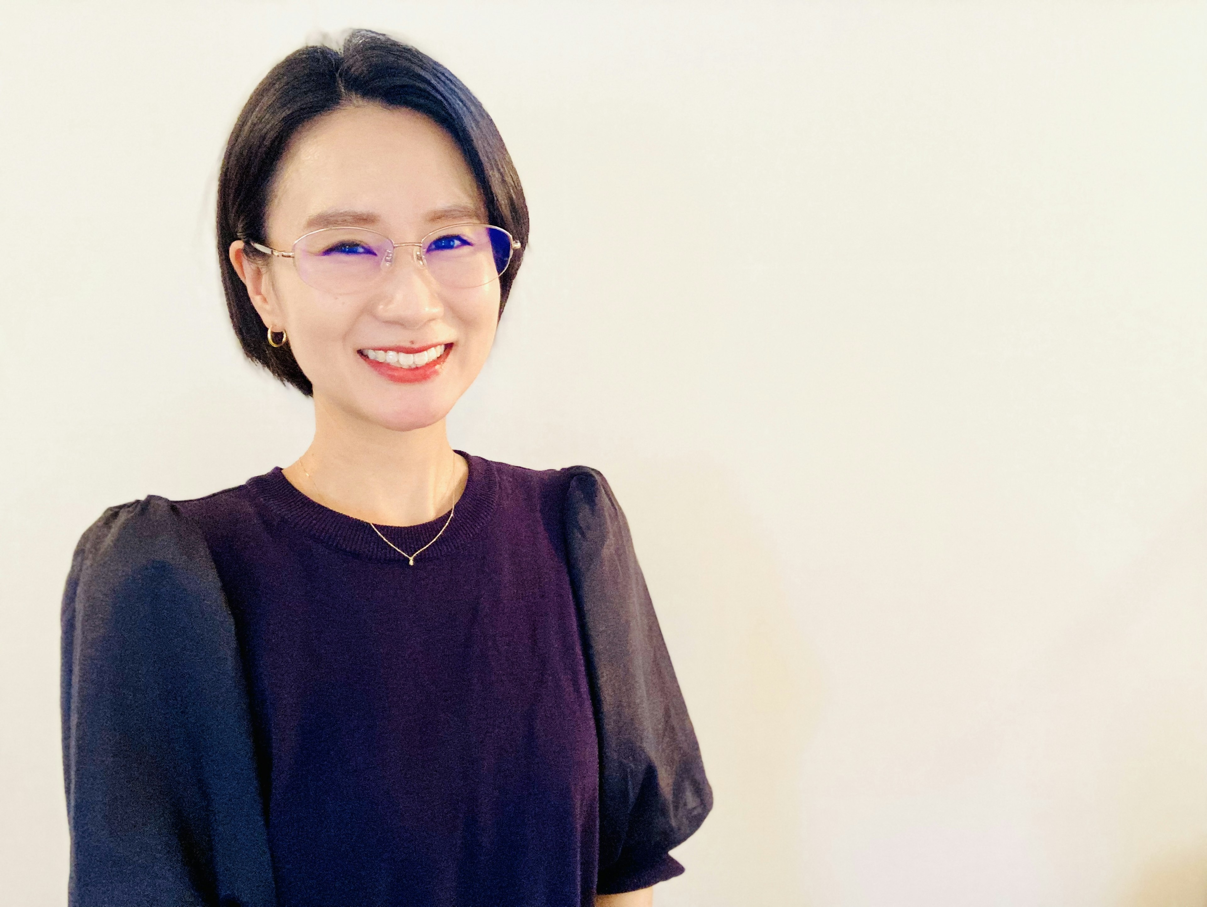 A woman smiling wearing a black dress against a white background