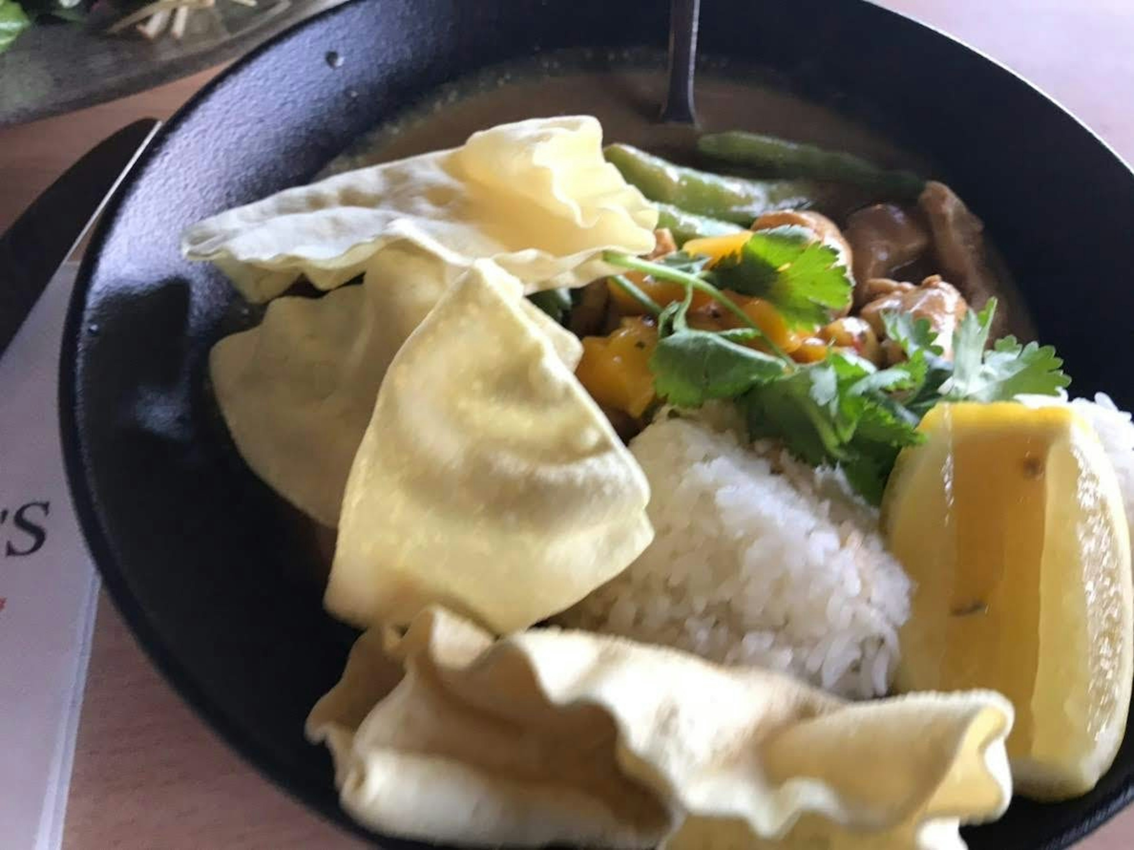 Un plat avec du curry, du riz et de la coriandre garni de crackers croustillants