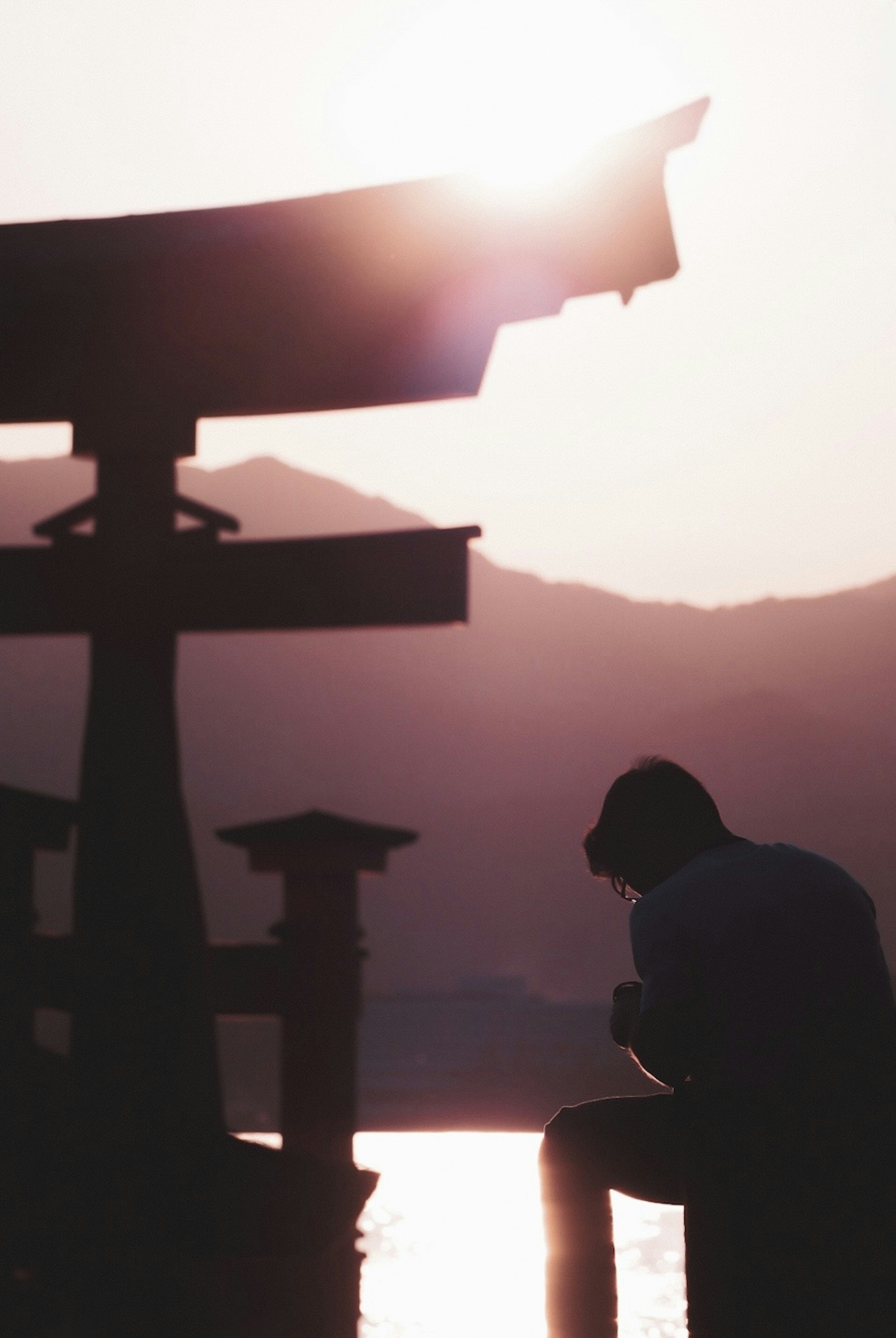 Silueta de una persona cerca de un torii al atardecer