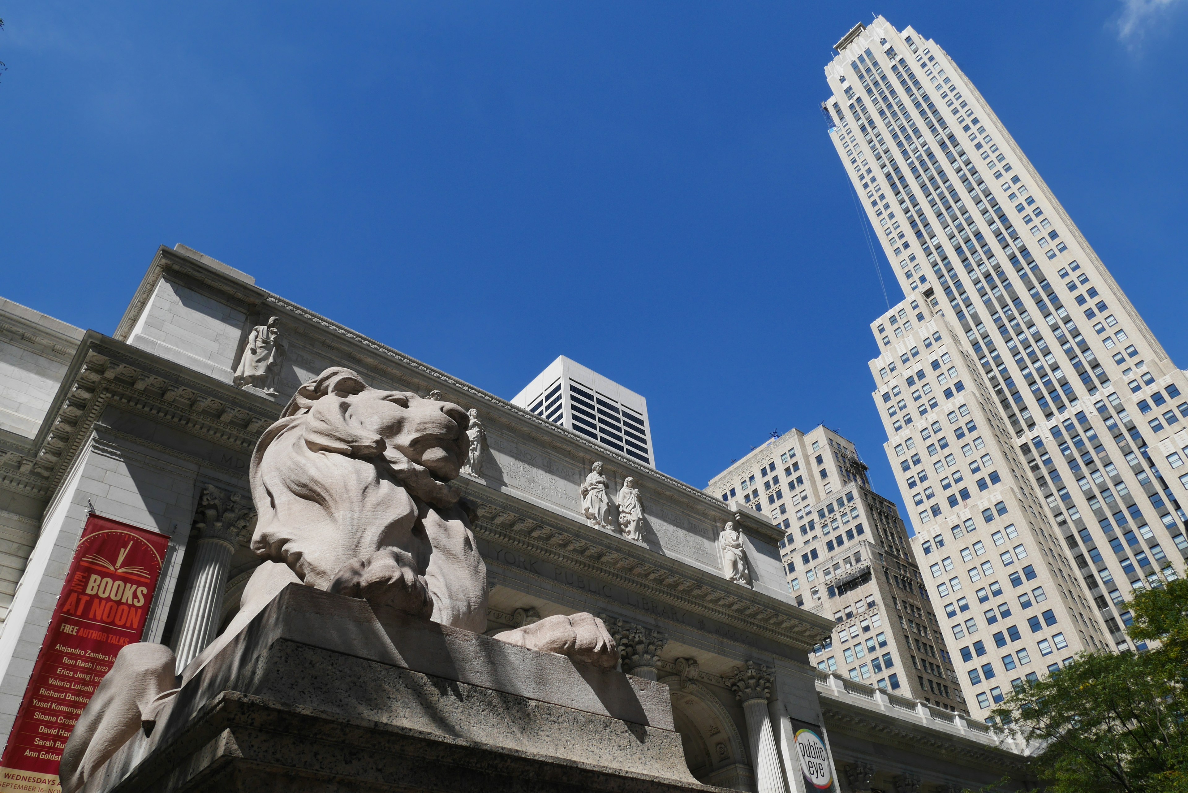 Lion sculpture in front of the Empire State Building against a blue sky