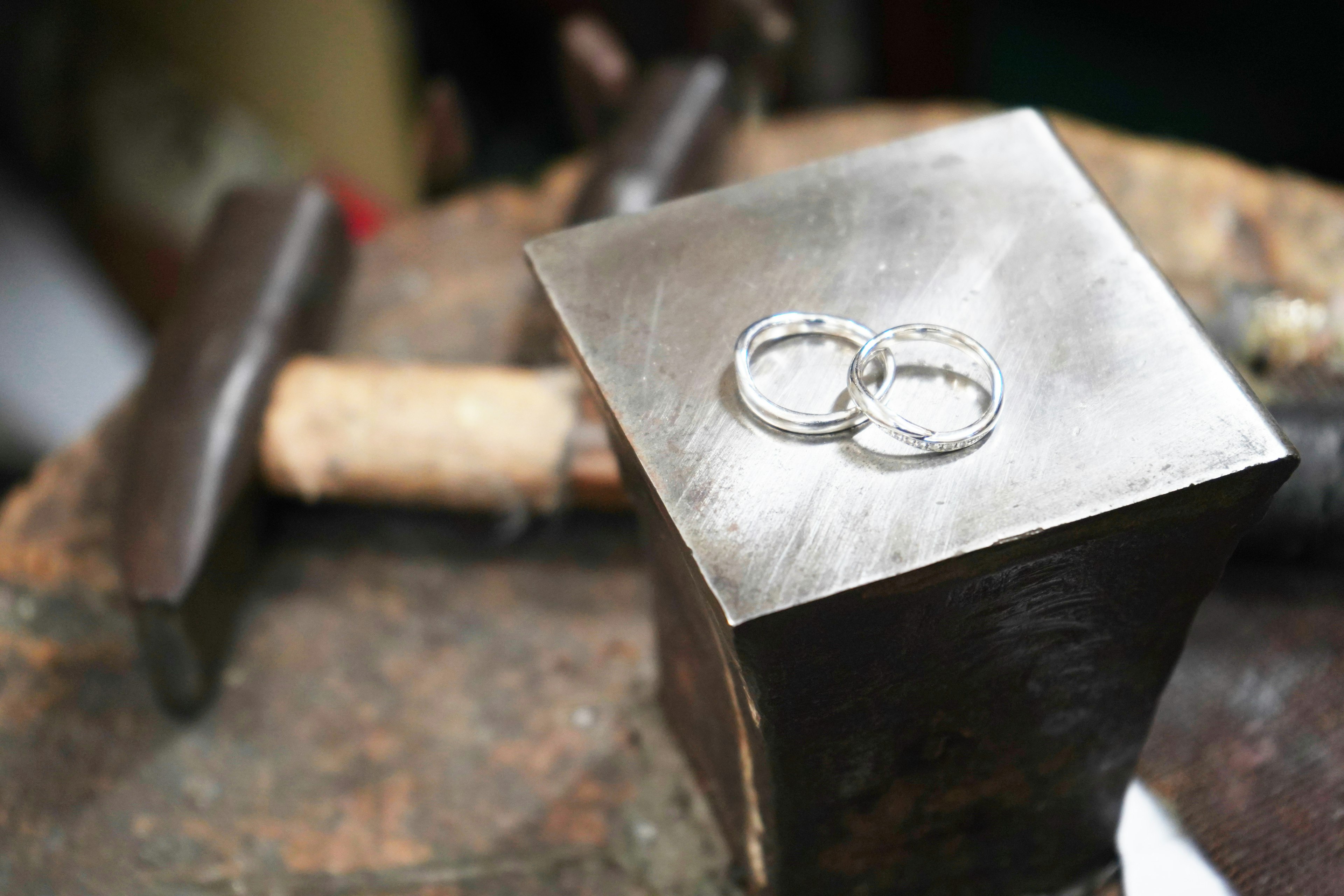 Dos anillos de plata colocados sobre un yunque metálico con herramientas de fondo