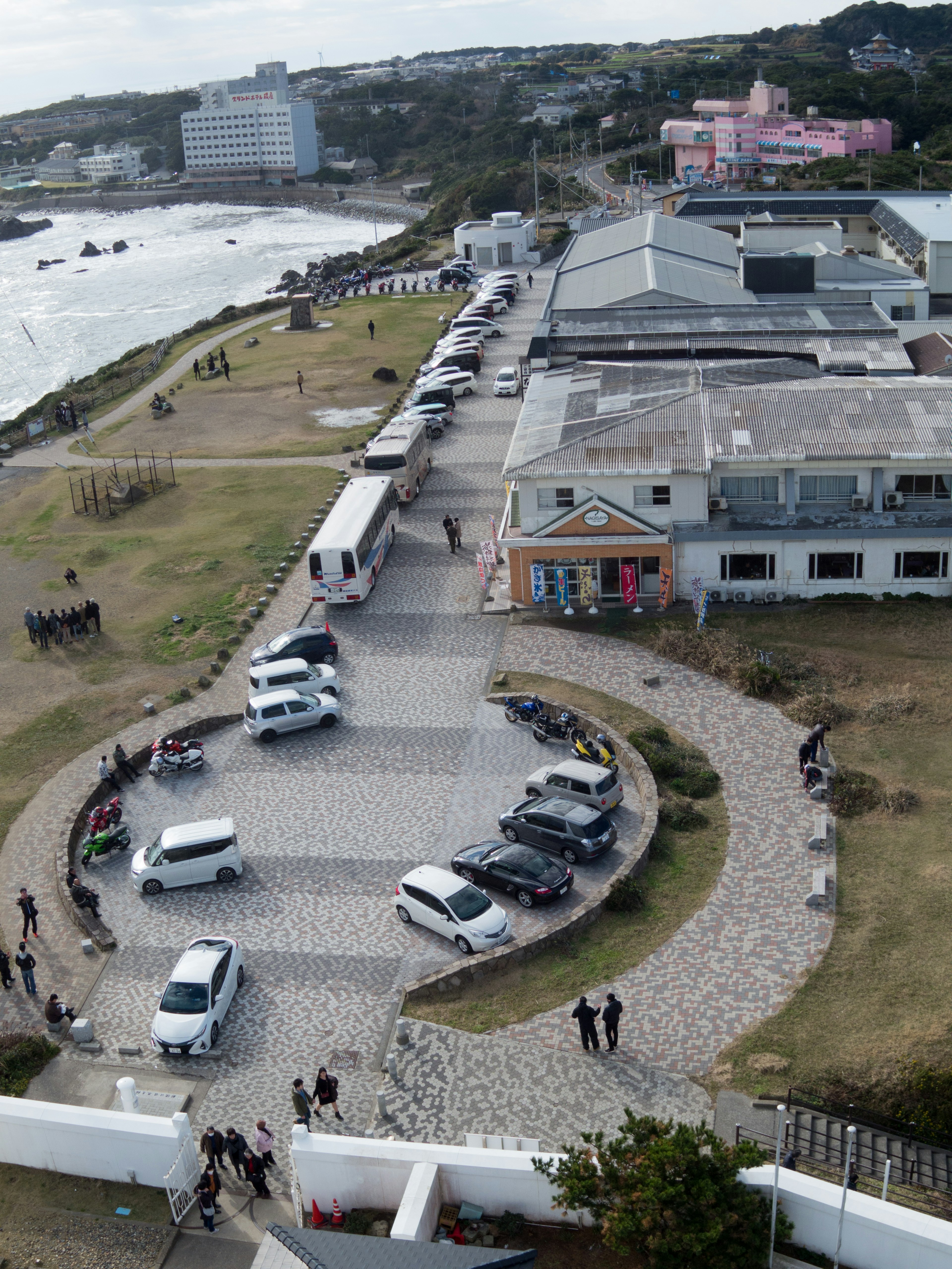 海岸沿いの建物と駐車場の上空視点が見える風景