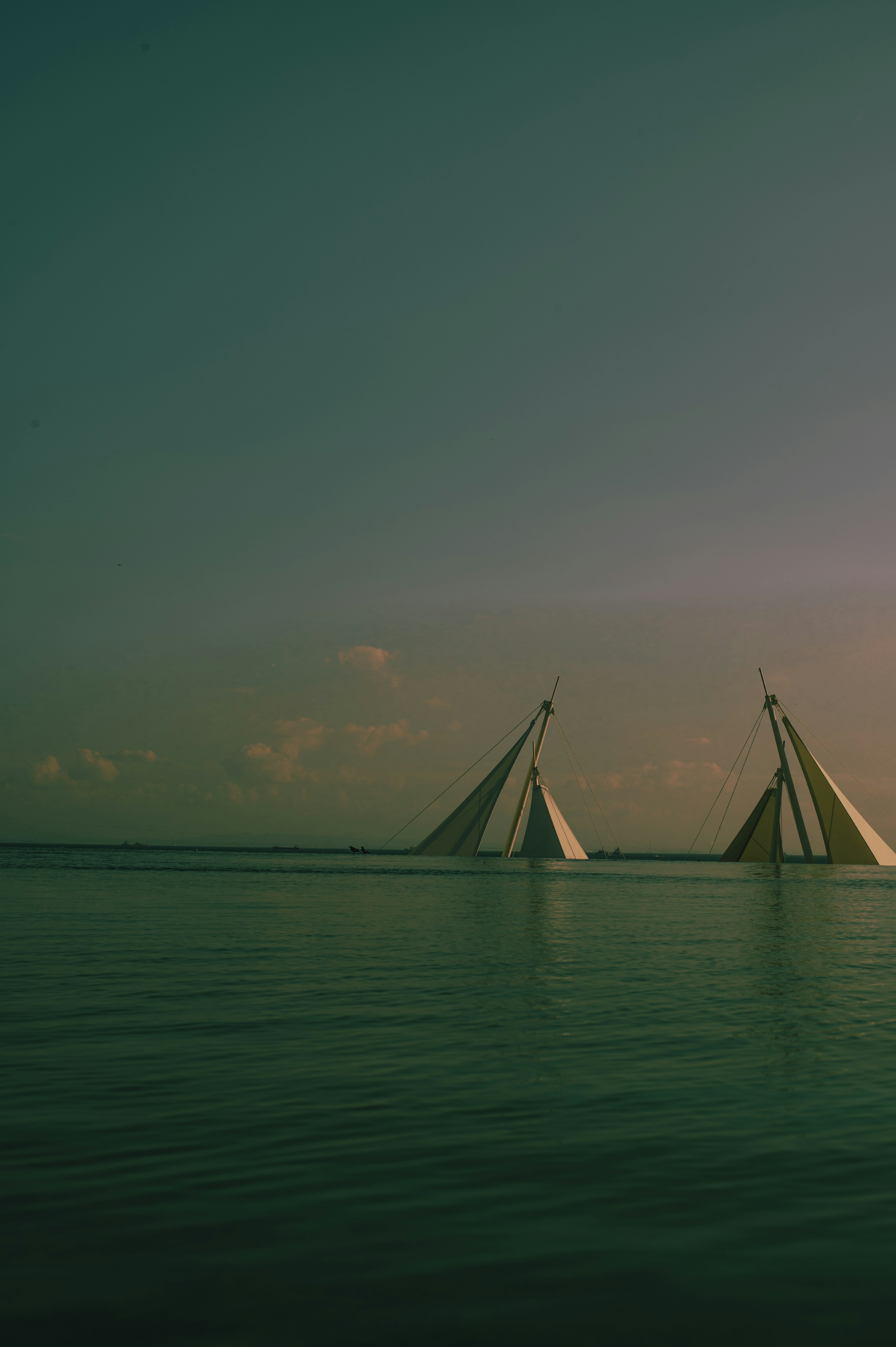 Two sailboats on a calm sea under a tranquil sky