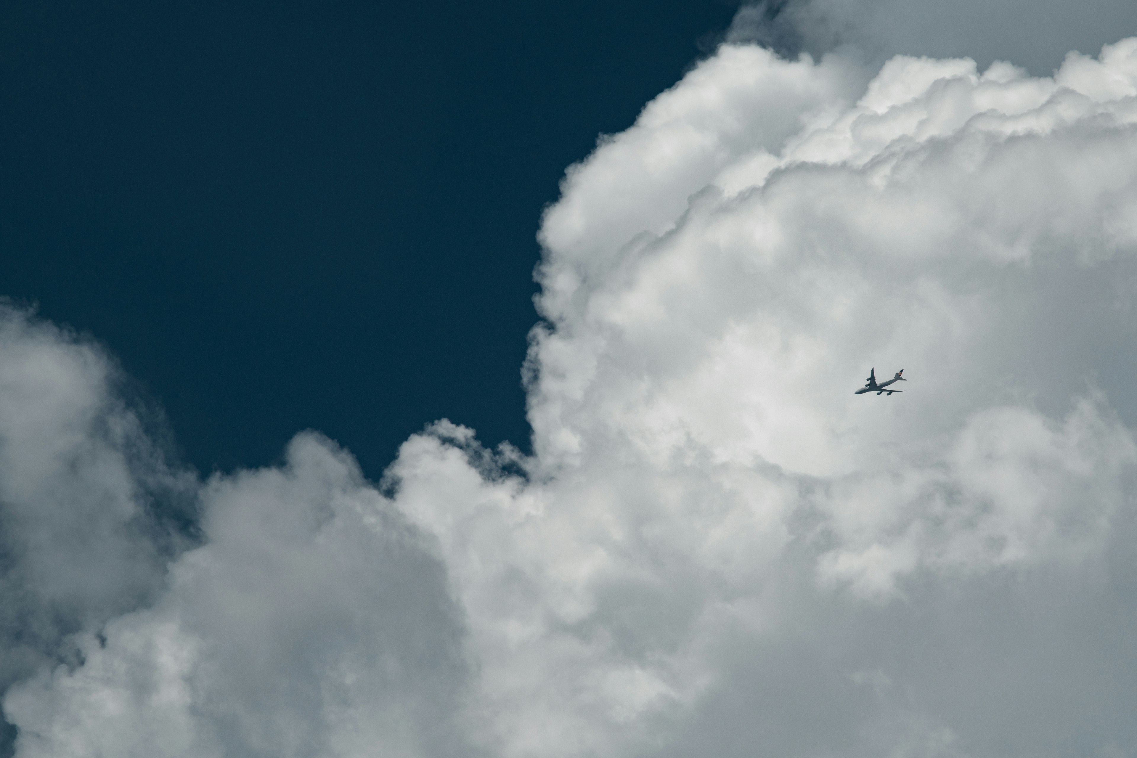 青い空に浮かぶ白い雲の間を飛ぶ飛行機