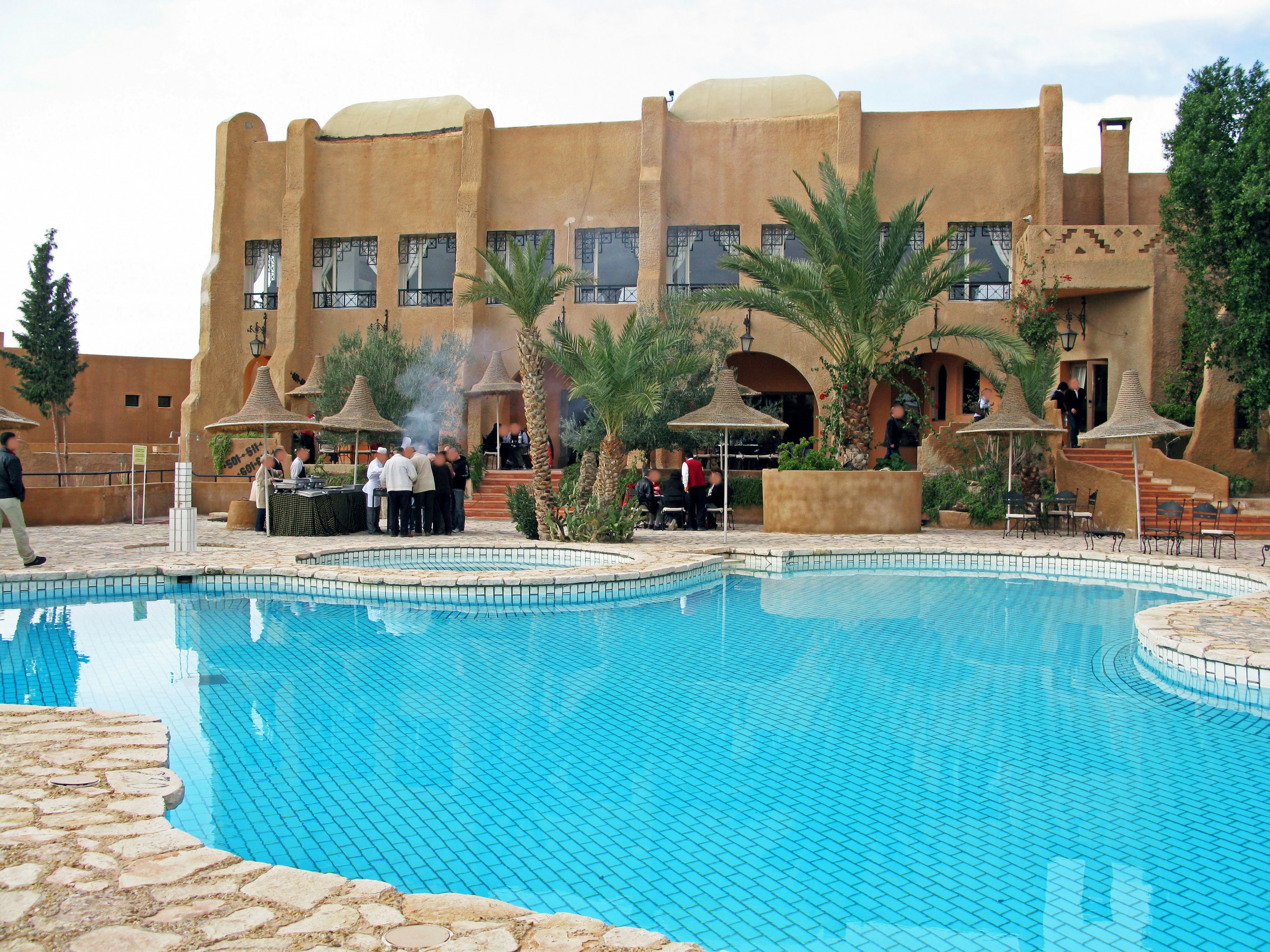 Edificio in stile marocchino con piscina blu e palme circostanti