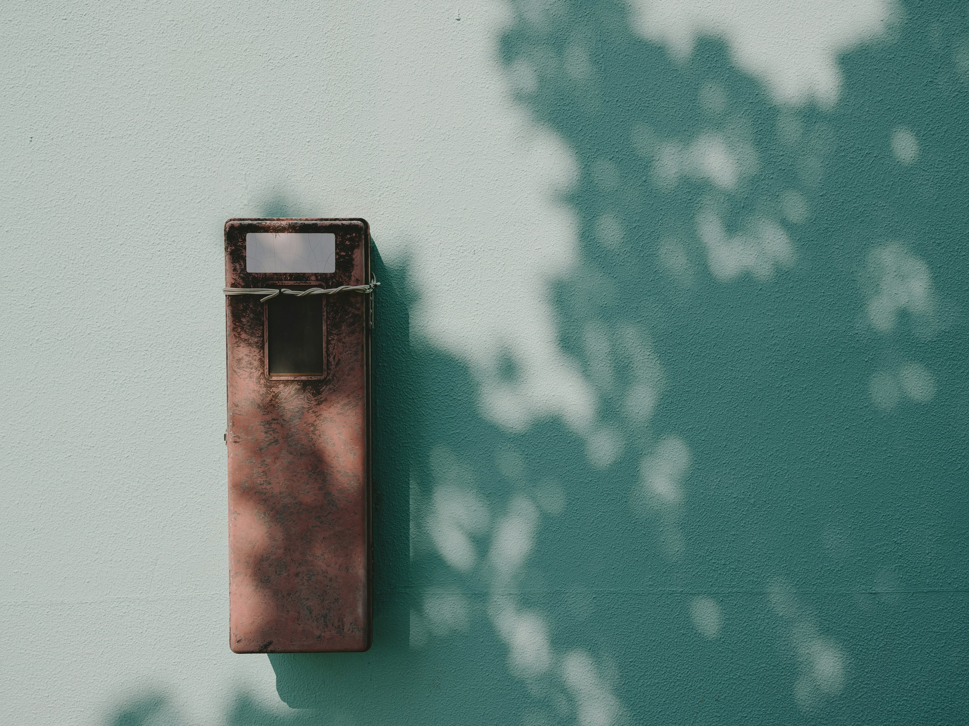 Alte Briefkasten an einer türkisfarbenen Wand mit sanften Schatten