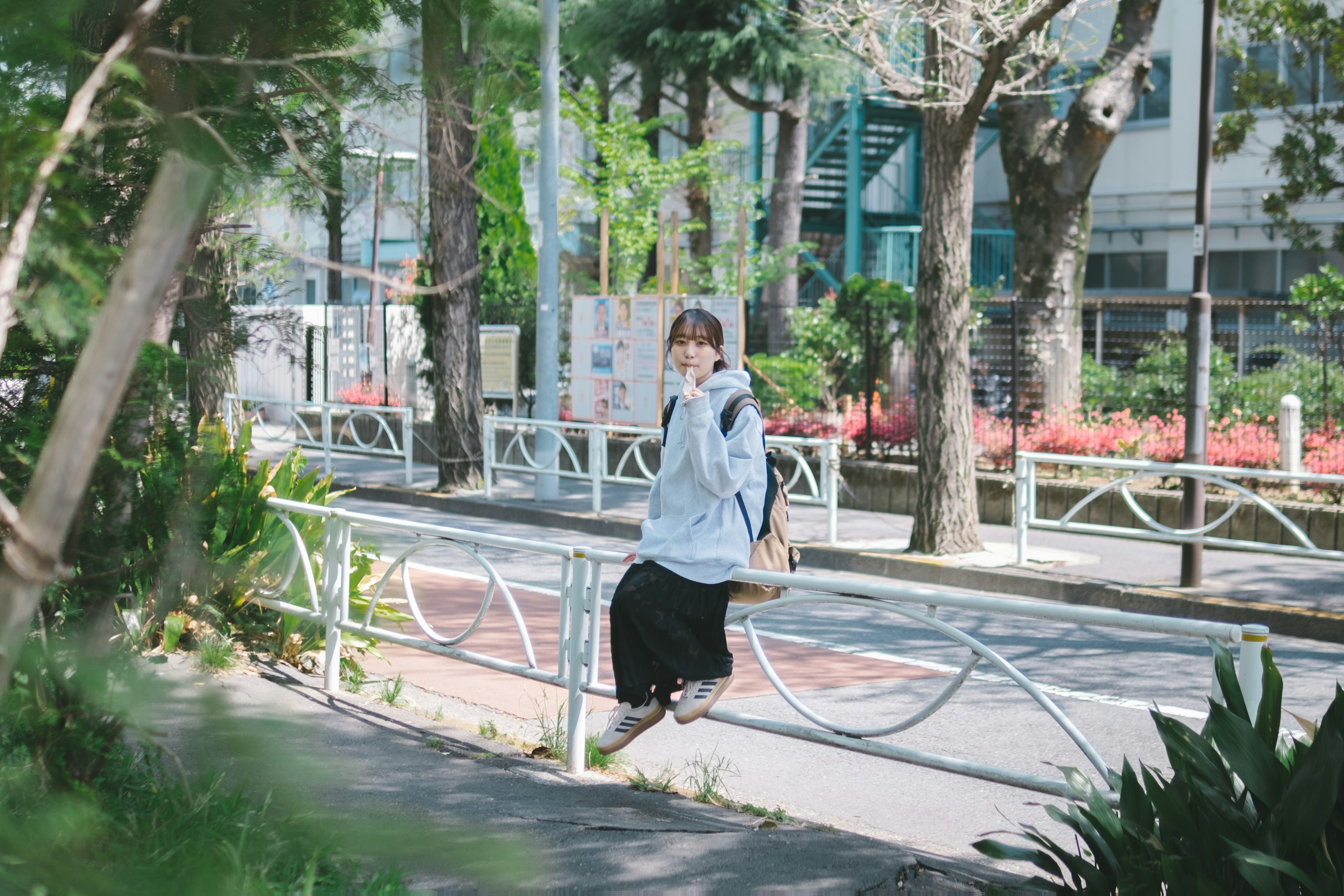 一位女士坐在公園長椅上 周圍環繞著綠樹和鮮花