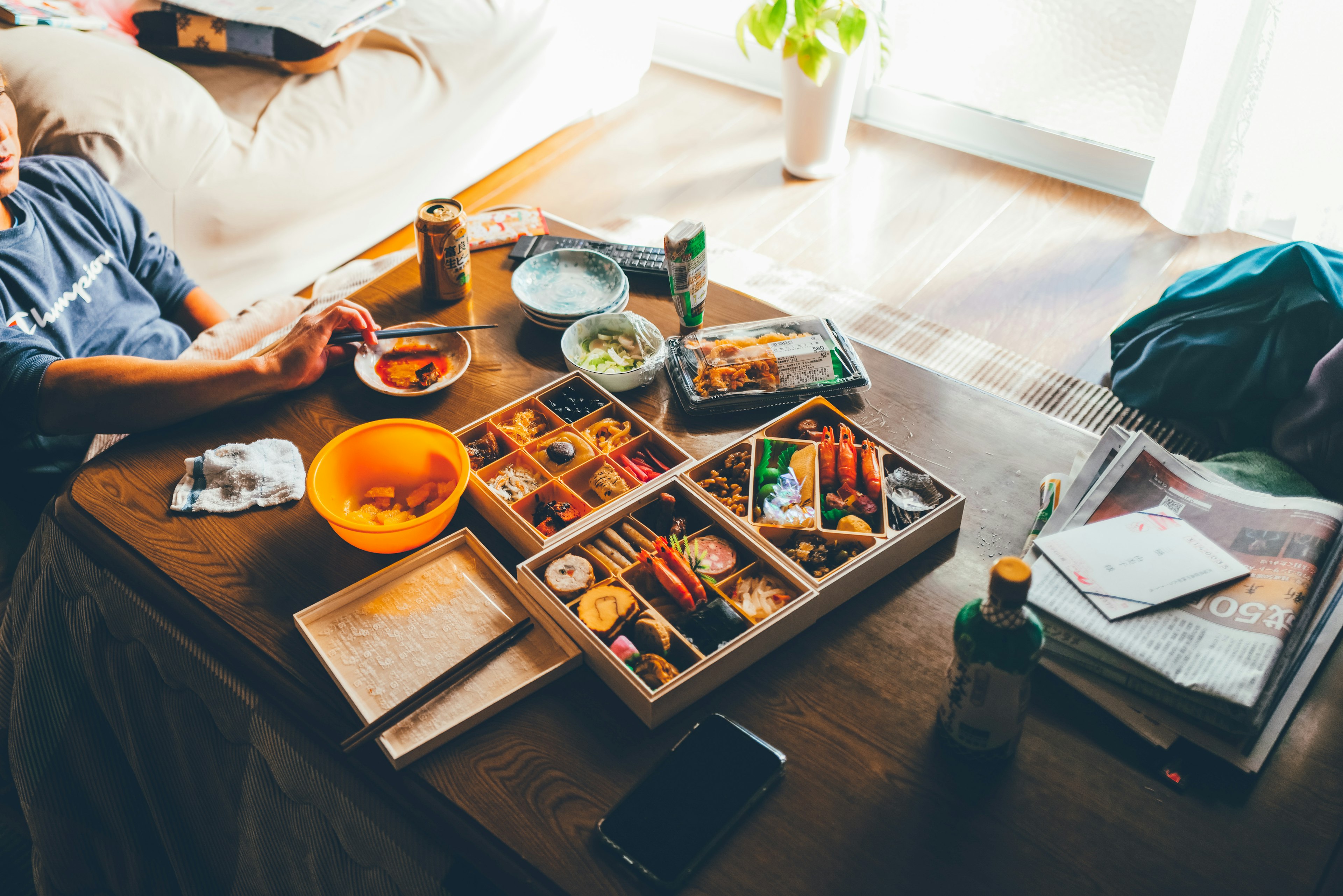 Una variedad de platos y bebidas esparcidos sobre una mesa con manos de personas