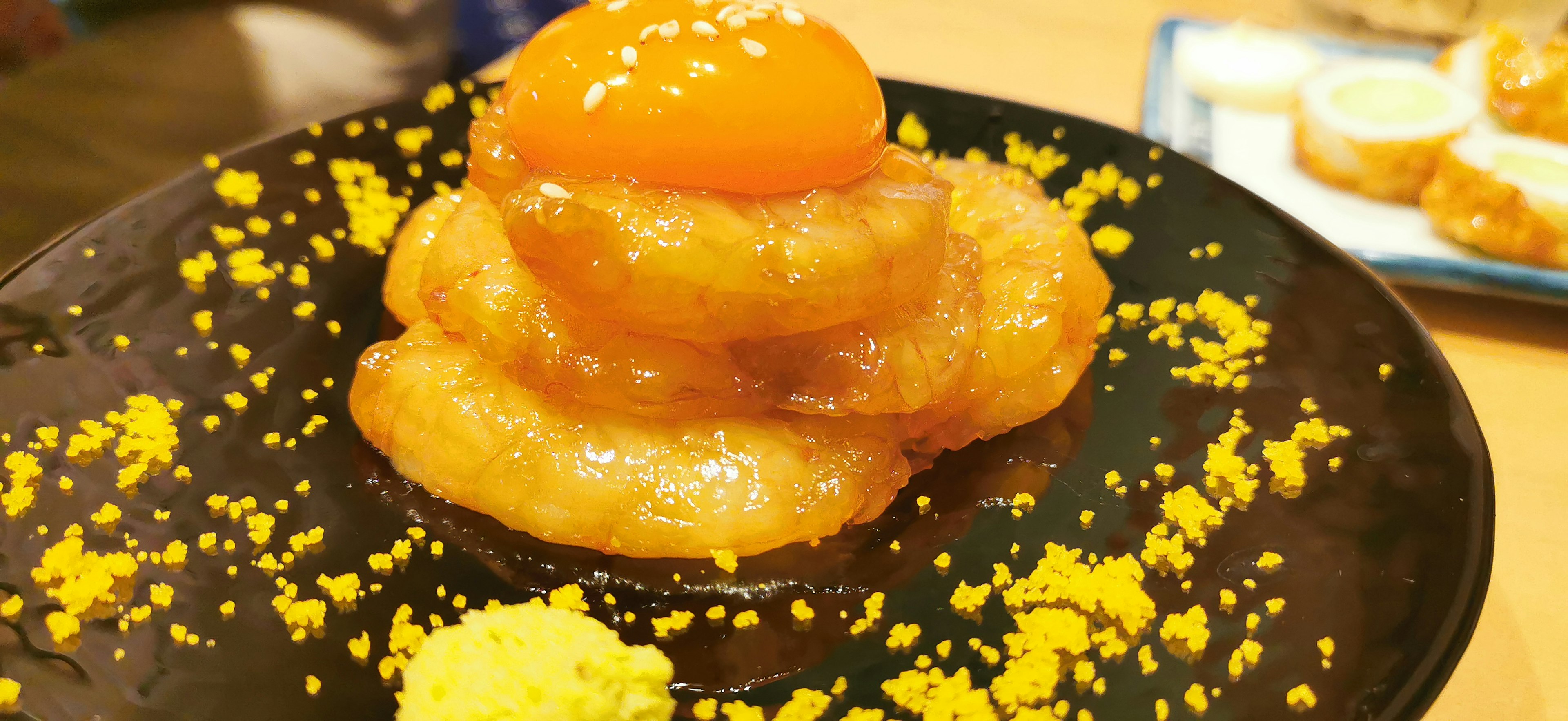 A photo of a sweet dessert served on a black plate featuring orange topping