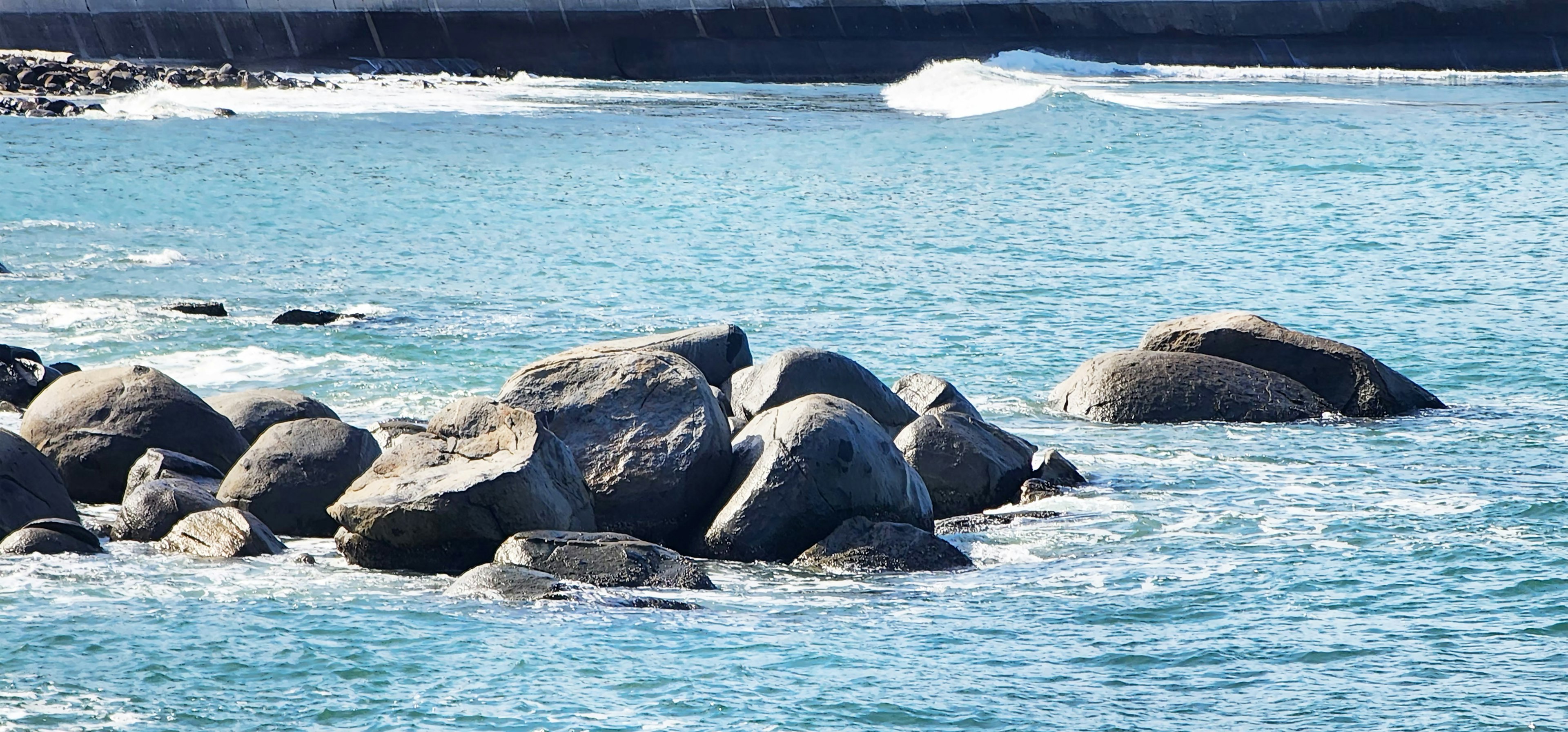 Large rocks in turquoise water with gentle waves