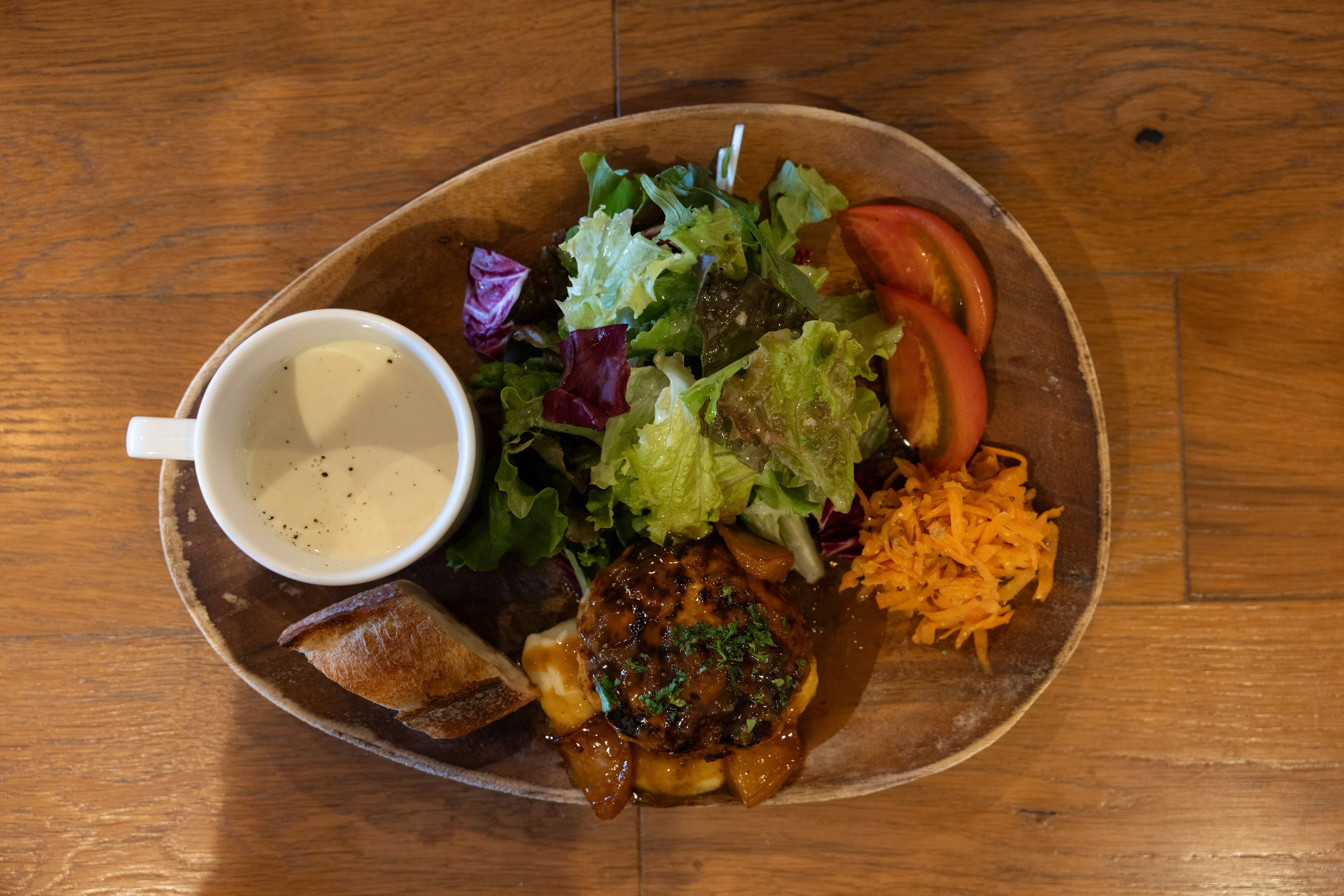 Món ăn trên đĩa gỗ với salad, cà chua, phô mai, súp và nem cuốn