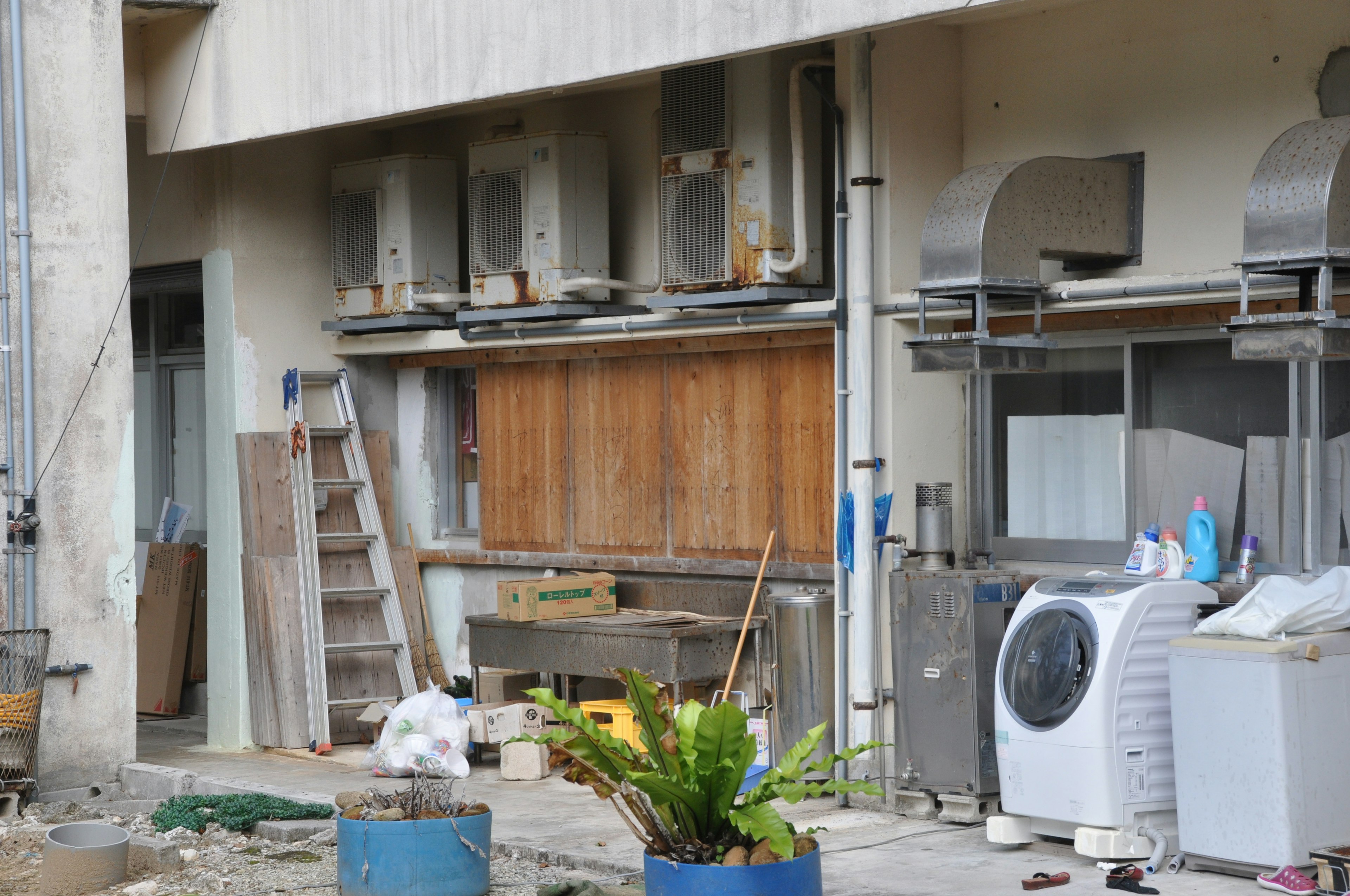 空調機が並ぶ建物の外壁と作業道具