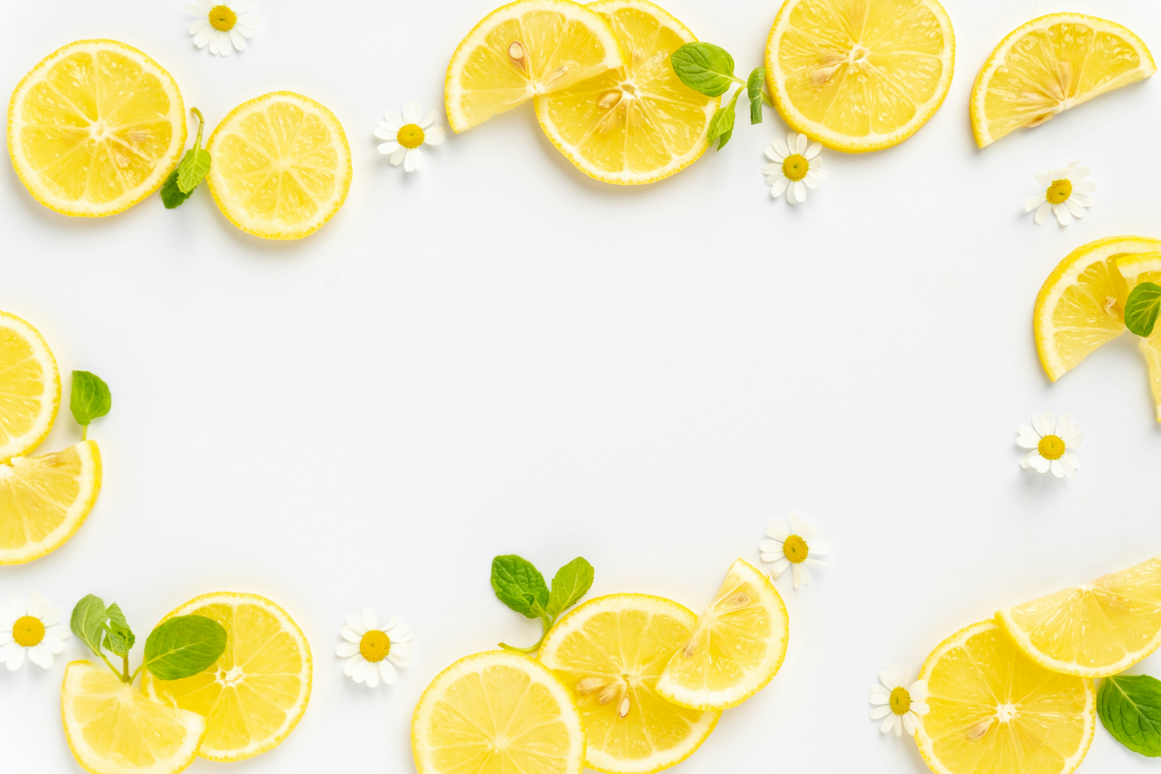 Sliced lemons and mint leaves arranged on a white background