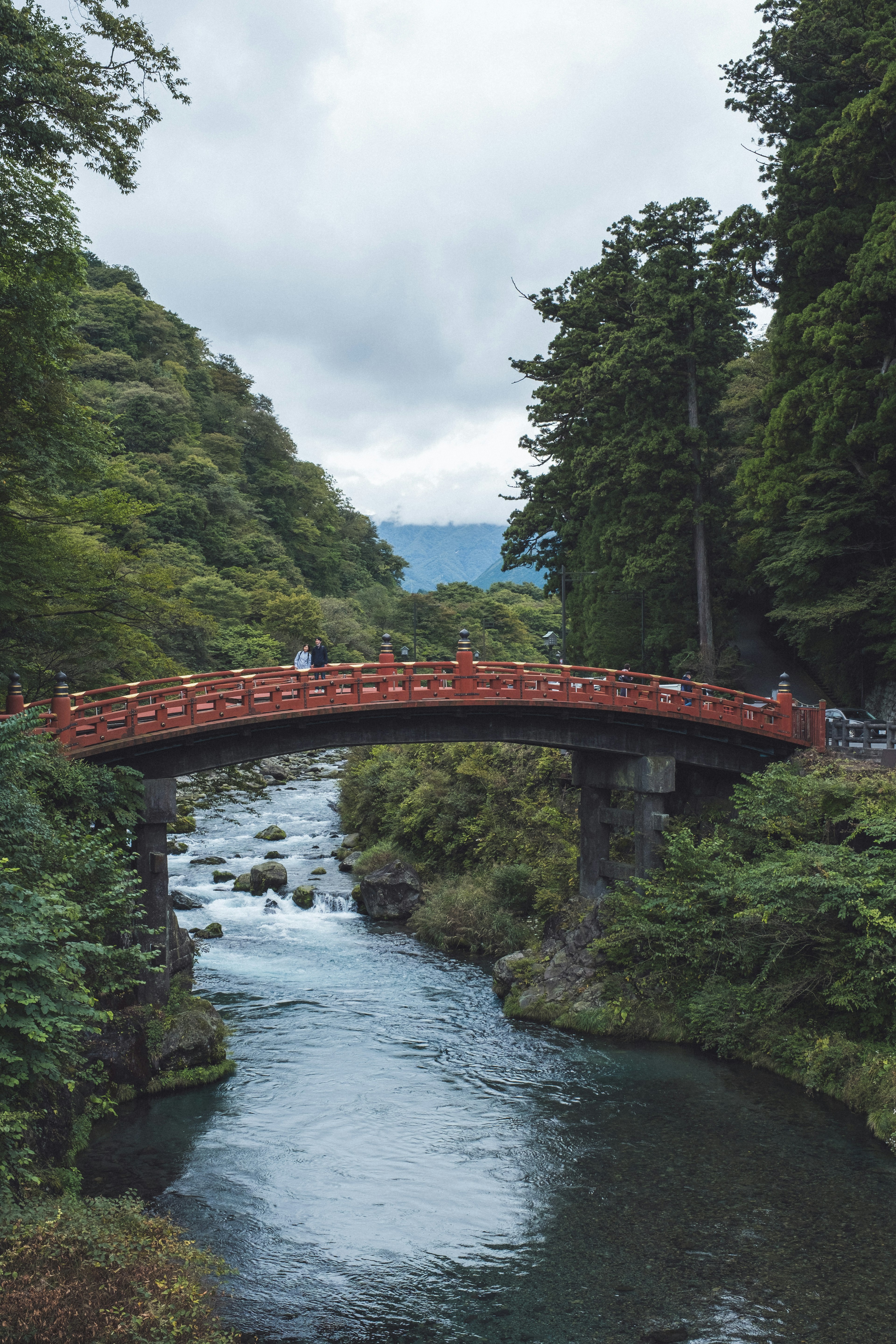 緑豊かな山々に囲まれた赤い橋と流れる川の風景