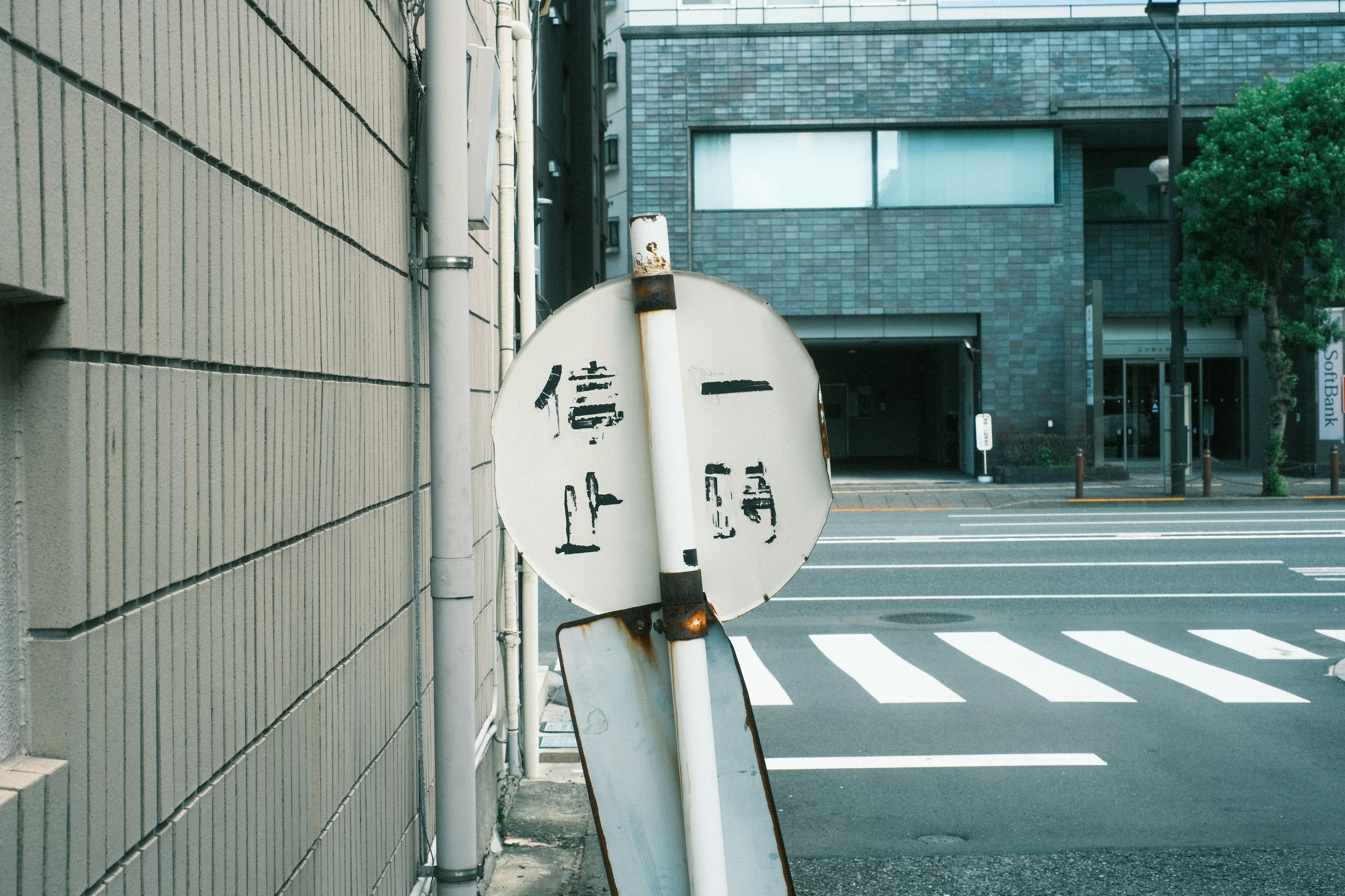 道路の歩行者信号を示す白い標識と背景の建物