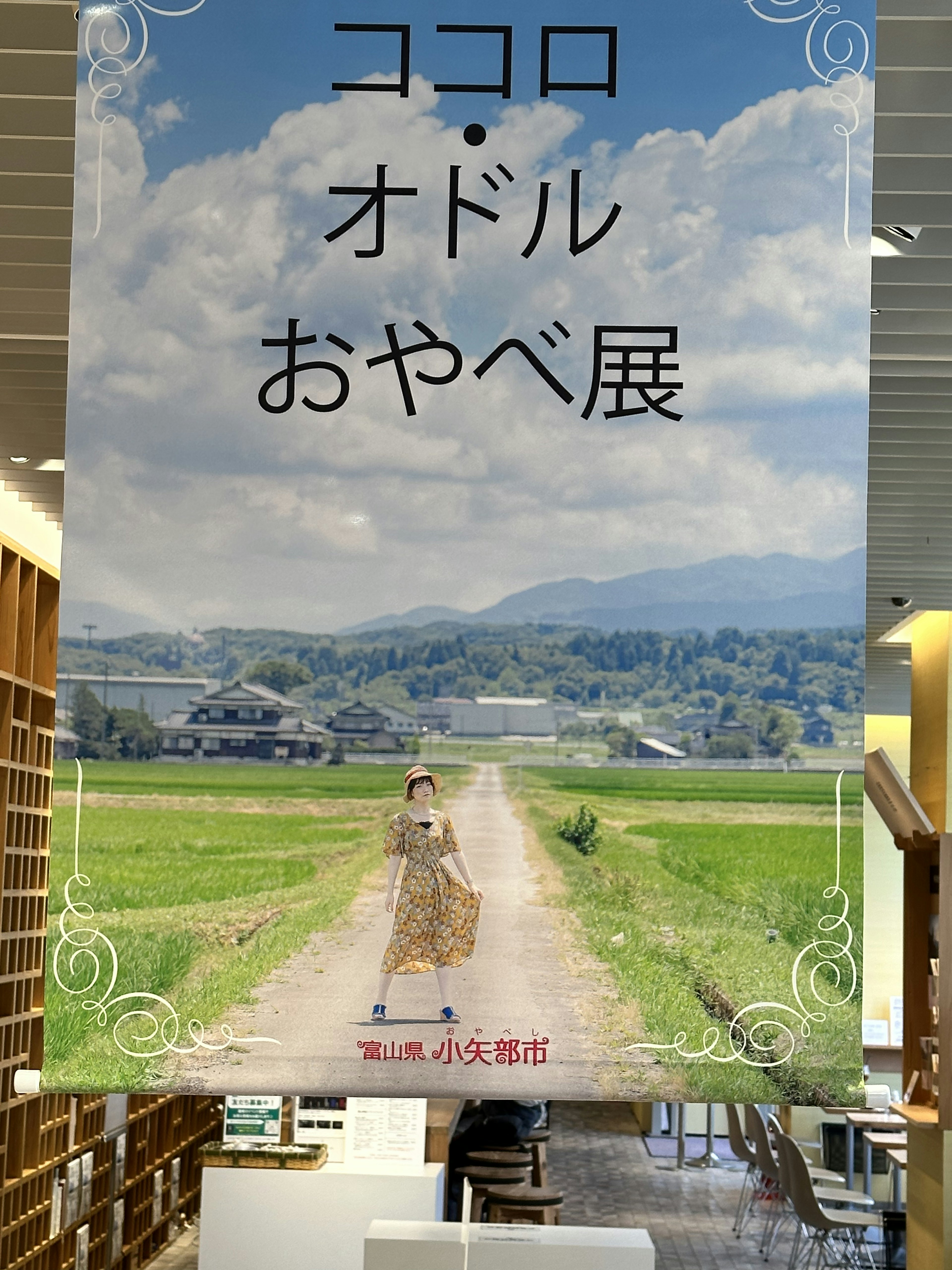 田園風景の中に立つ女性のポスター ココロ・オドルおやべ展