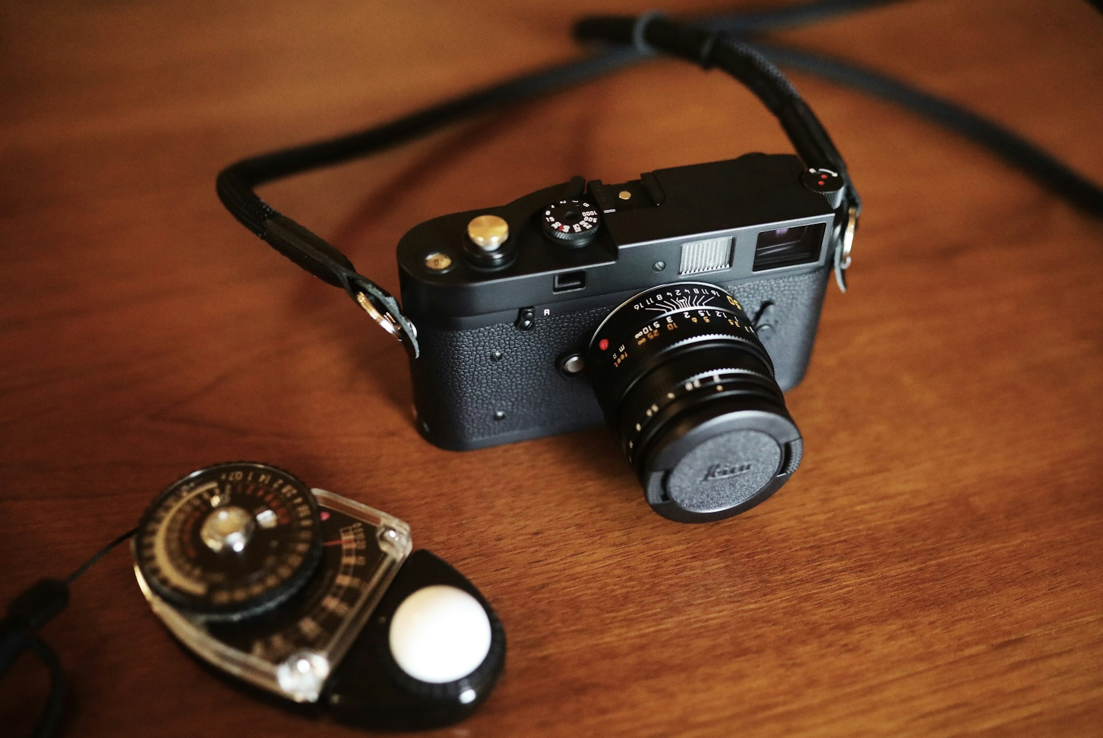 Black camera and light meter placed on a wooden table