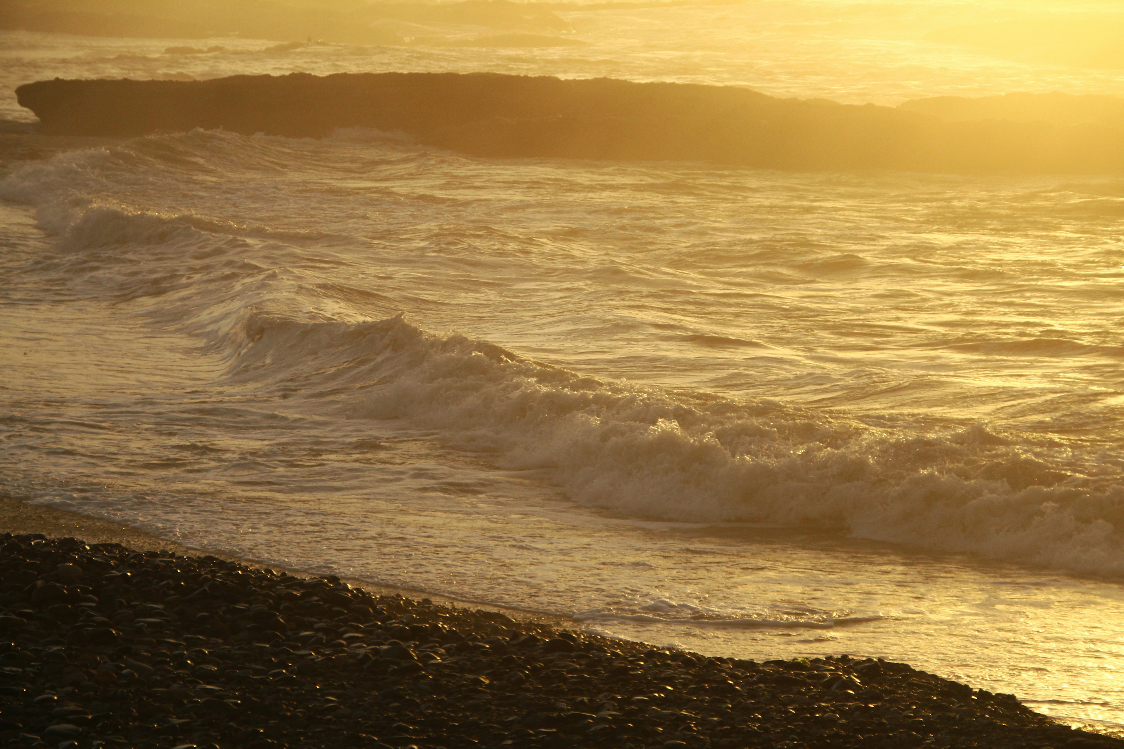 Wellen an einem Strand mit goldenem Sonnenuntergang