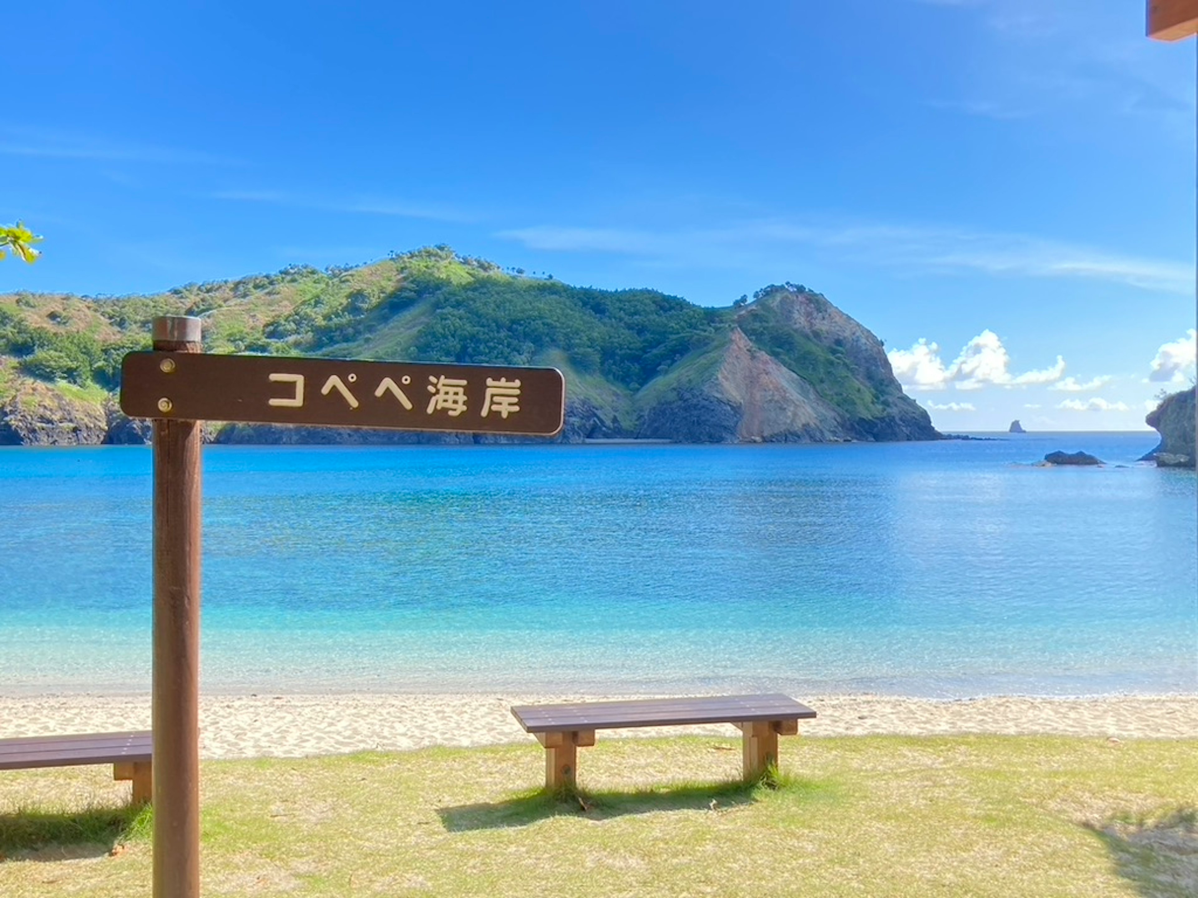 青い海と山々が広がる美しいビーチ コベベ海岸の看板が目立つ