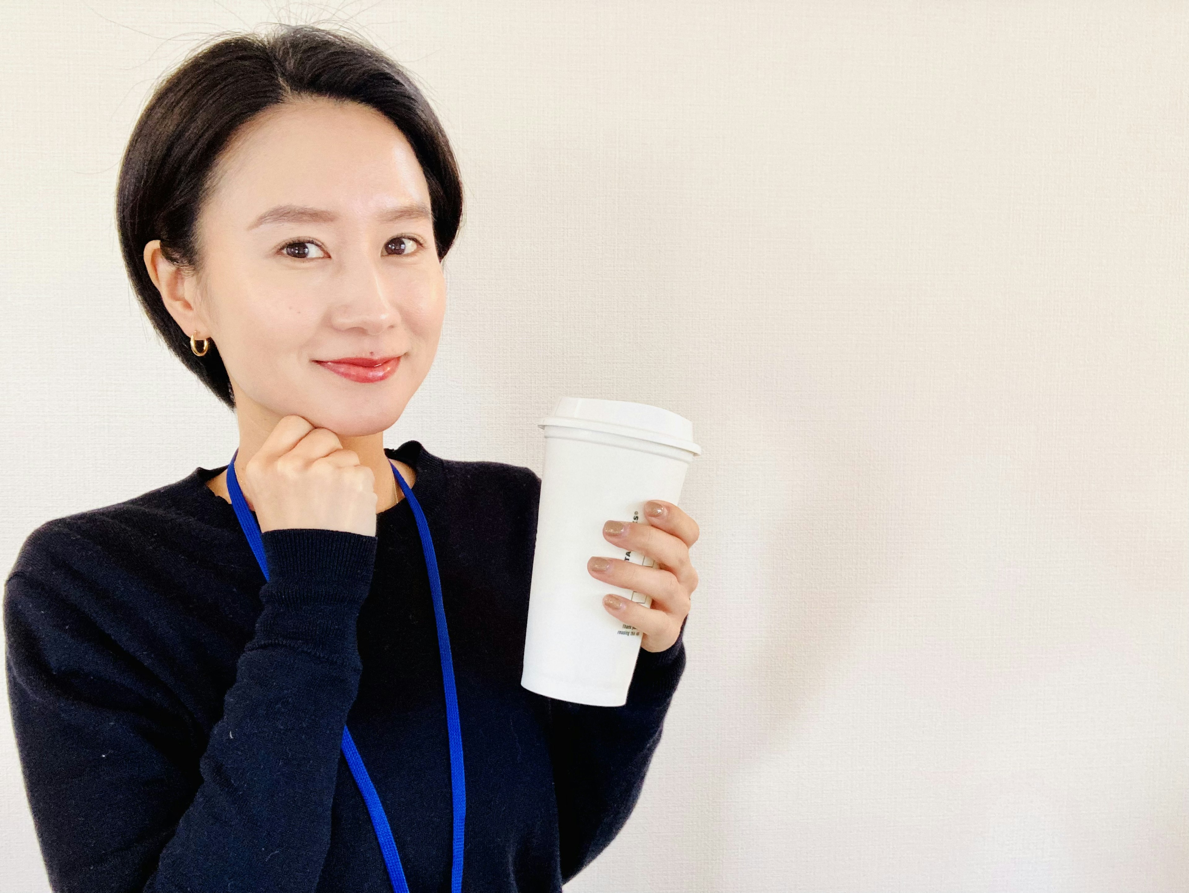 Mujer sonriendo mientras sostiene una taza de café blanca